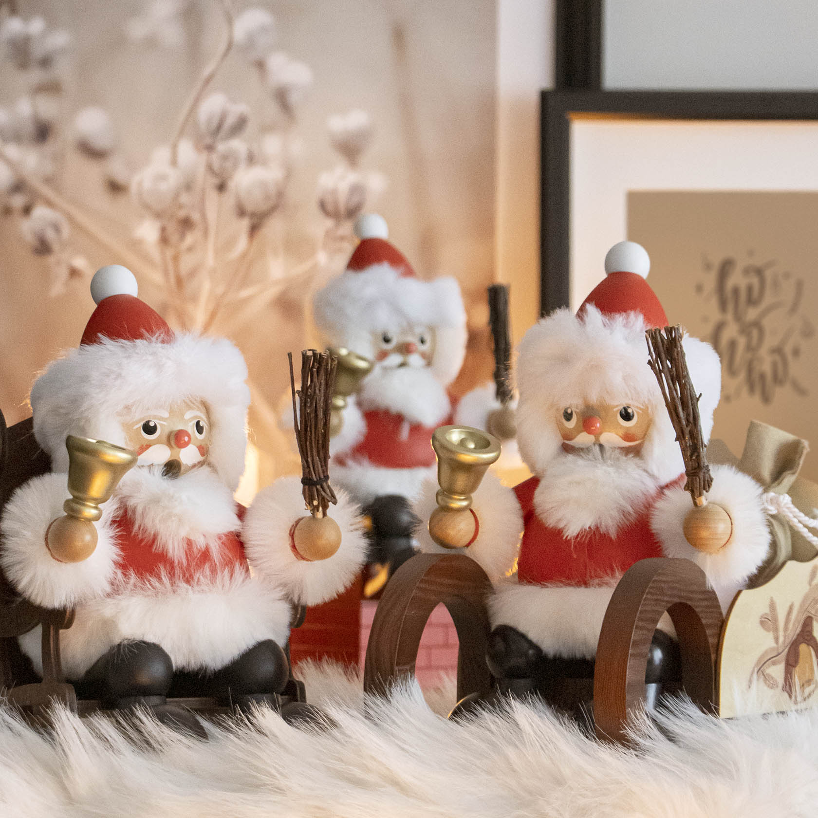 Drei Räuchermänner in Form von Weihnachtsmännern sitzen auf Schlitten. Jeder hält eine Glocke und Rute in den Händen.