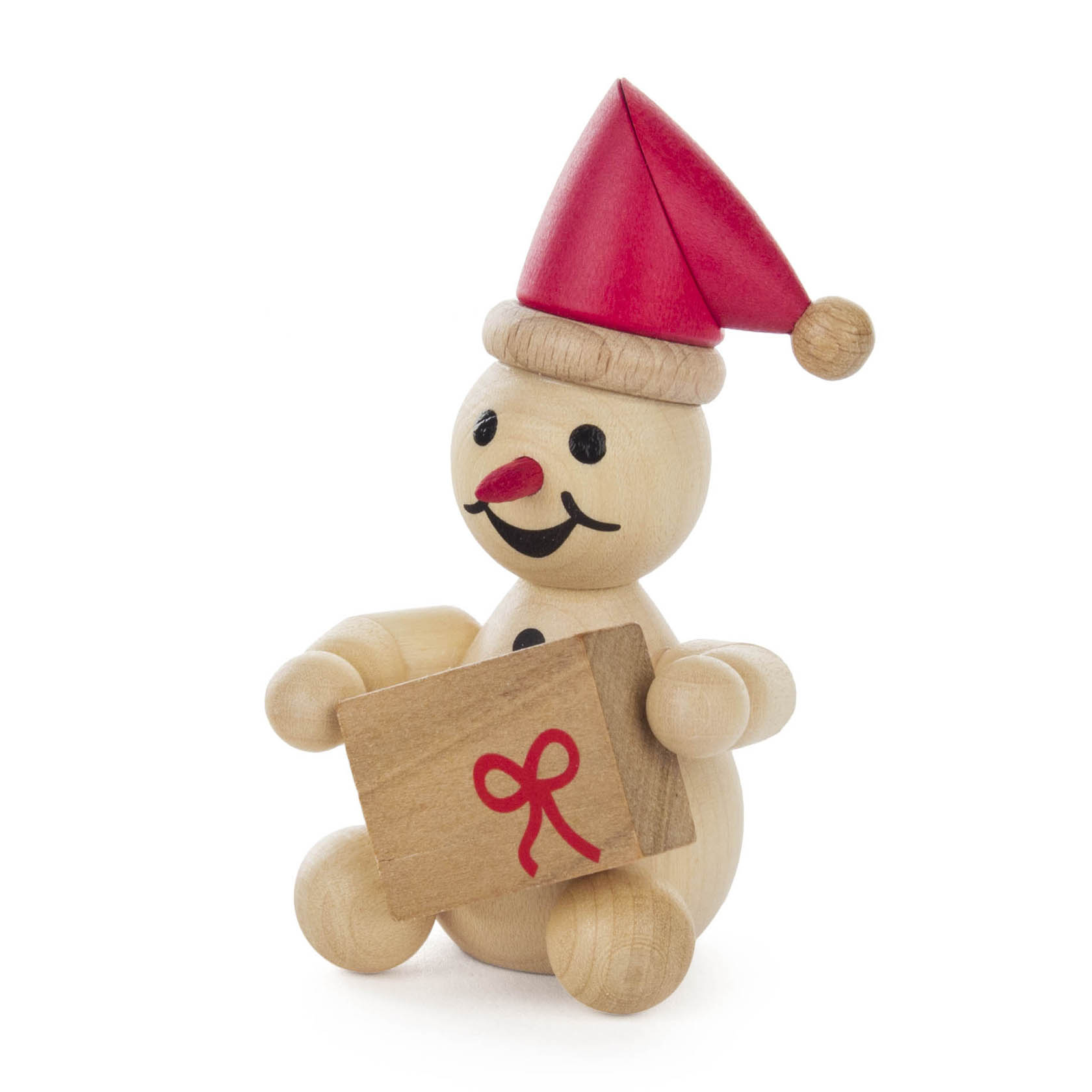 Ein Holzfigur-Schneemann mit roter Mütze, schwarzem Gesicht und Karottennase, hält ein Geschenk mit roter Schleife in den Händen. im Dregeno Online Shop günstig kaufen