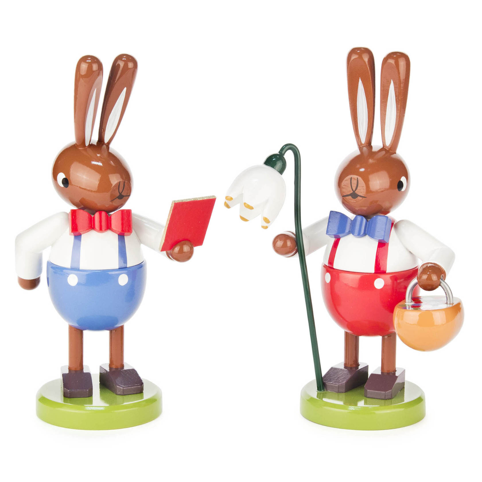 Zwei Holzhäschen in roter und blauer Kleidung, einer mit Korb und Blume, der andere mit einem Buch. Beide tragen Fliegen. im Dregeno Online Shop günstig kaufen