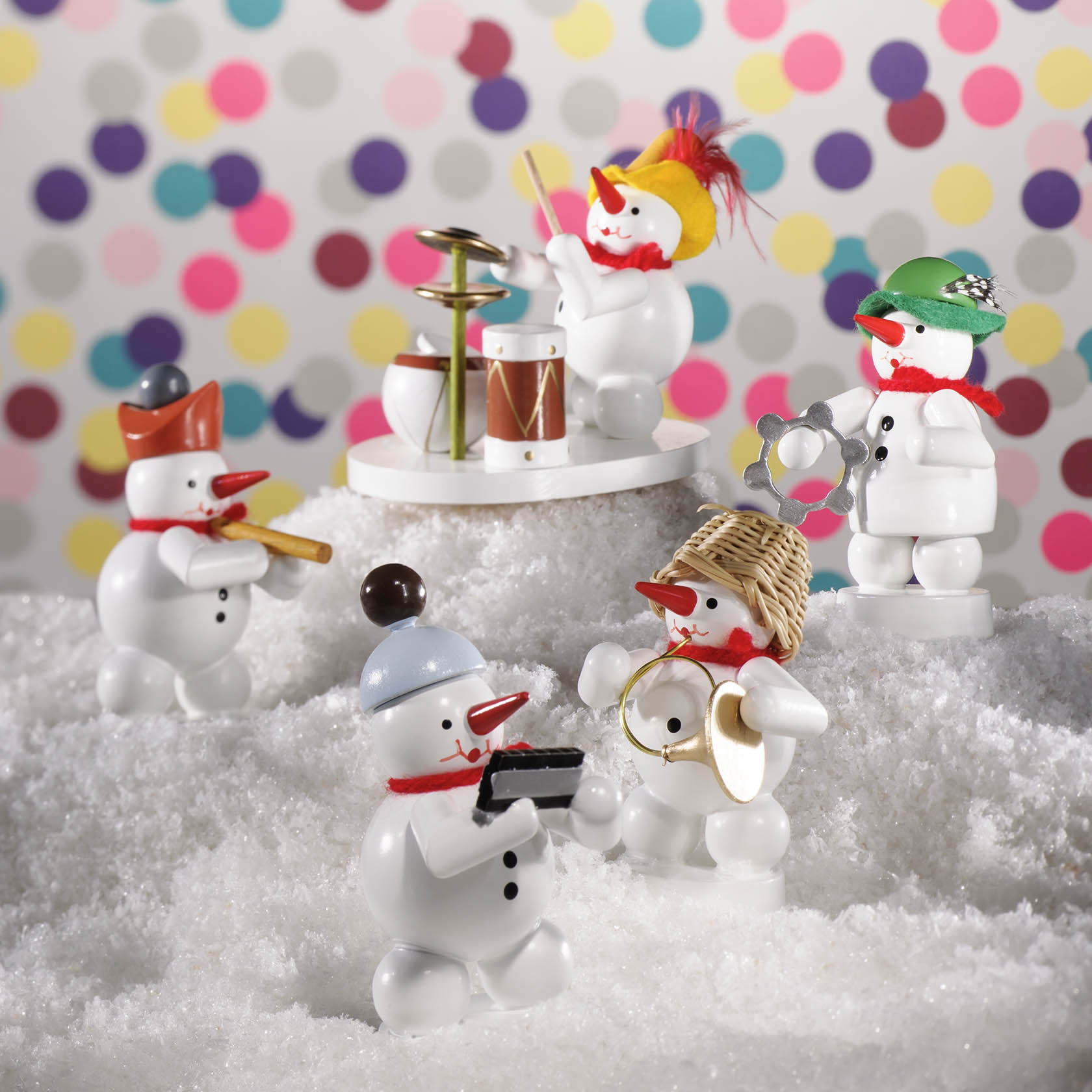 Fünf Schneemann-Figuren, die Musikinstrumente spielen: Zwei Schlagzeuge, ein Waldhorn, eine Trompete und ein Akkordeon in einer Schneelandschaft.