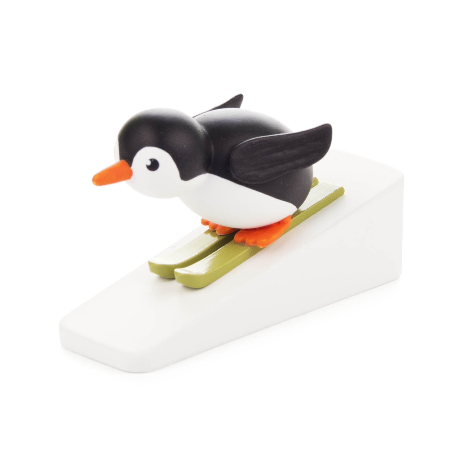 Ein Spielzeugpinguin mit ausgebreiteten Flügeln steht auf zwei grünen Skiern auf einer weißen Rampe, bereit zum Skispringen. im Dregeno Online Shop günstig kaufen