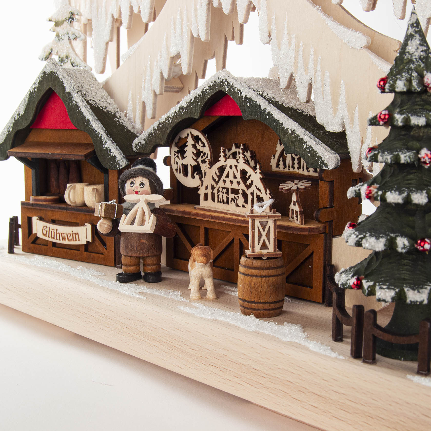 Ein kleiner Schwibbogen auf einem Weihnachtsmarkt mit Holzfiguren: Ein Mann hält einen Krug, ein Hund steht daneben, Verkaufsstände sind geschmückt.