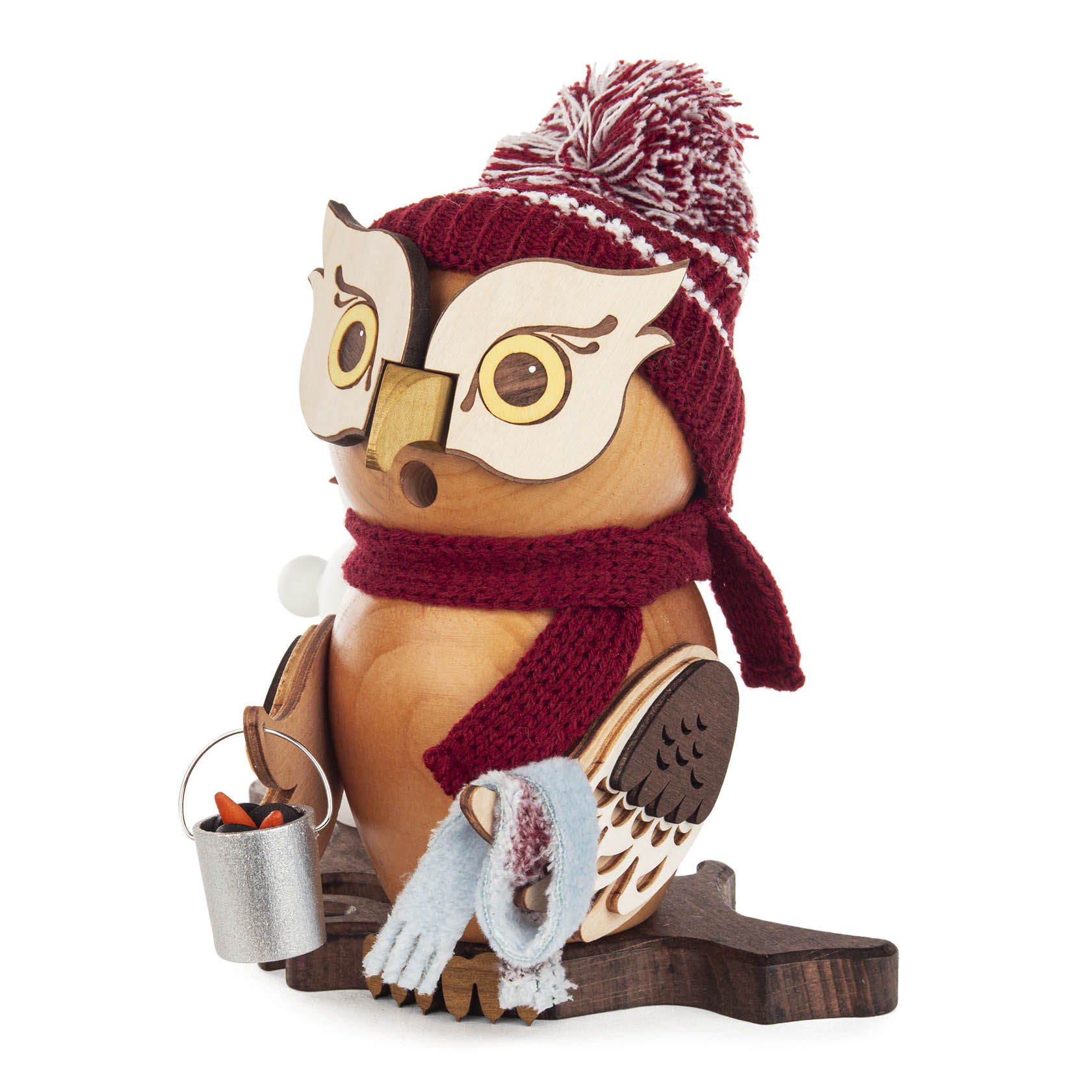 Holzeule mit roter Mütze und Schal, hält eine kleine Metalltonne mit Karotten und trägt einen Schneemann aus Watte auf einem Ast.