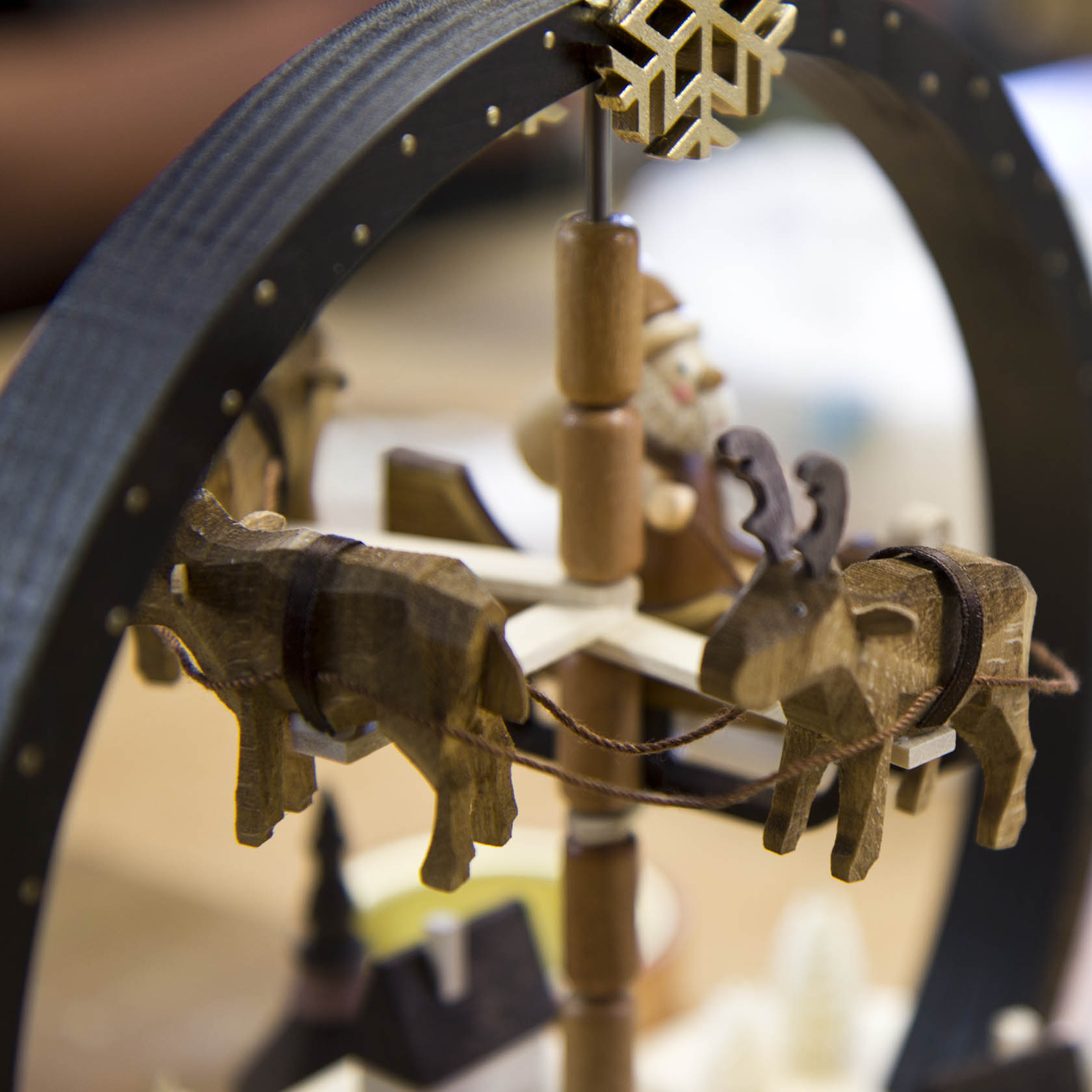 Close-up of a wooden Christmas pyramid featuring reindeer figures rotating around a central axis, with a snowflake decoration on top. im Dregeno Online Shop günstig kaufen