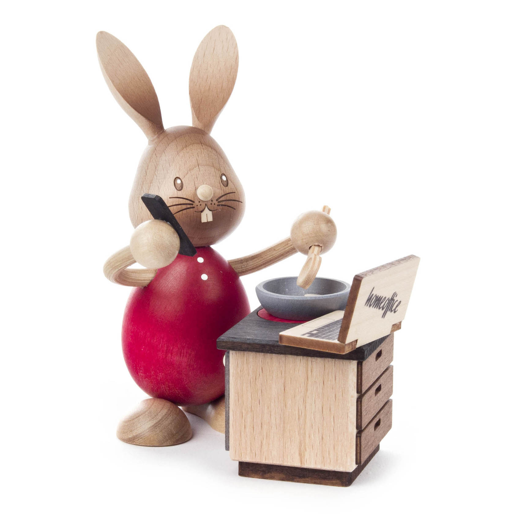 Holzfigur eines Hasen mit rotem Bauch steht vor einem Holztisch, hält ein Smartphone ans Ohr und eine Karotte, als ob er im Homeoffice arbeitet.