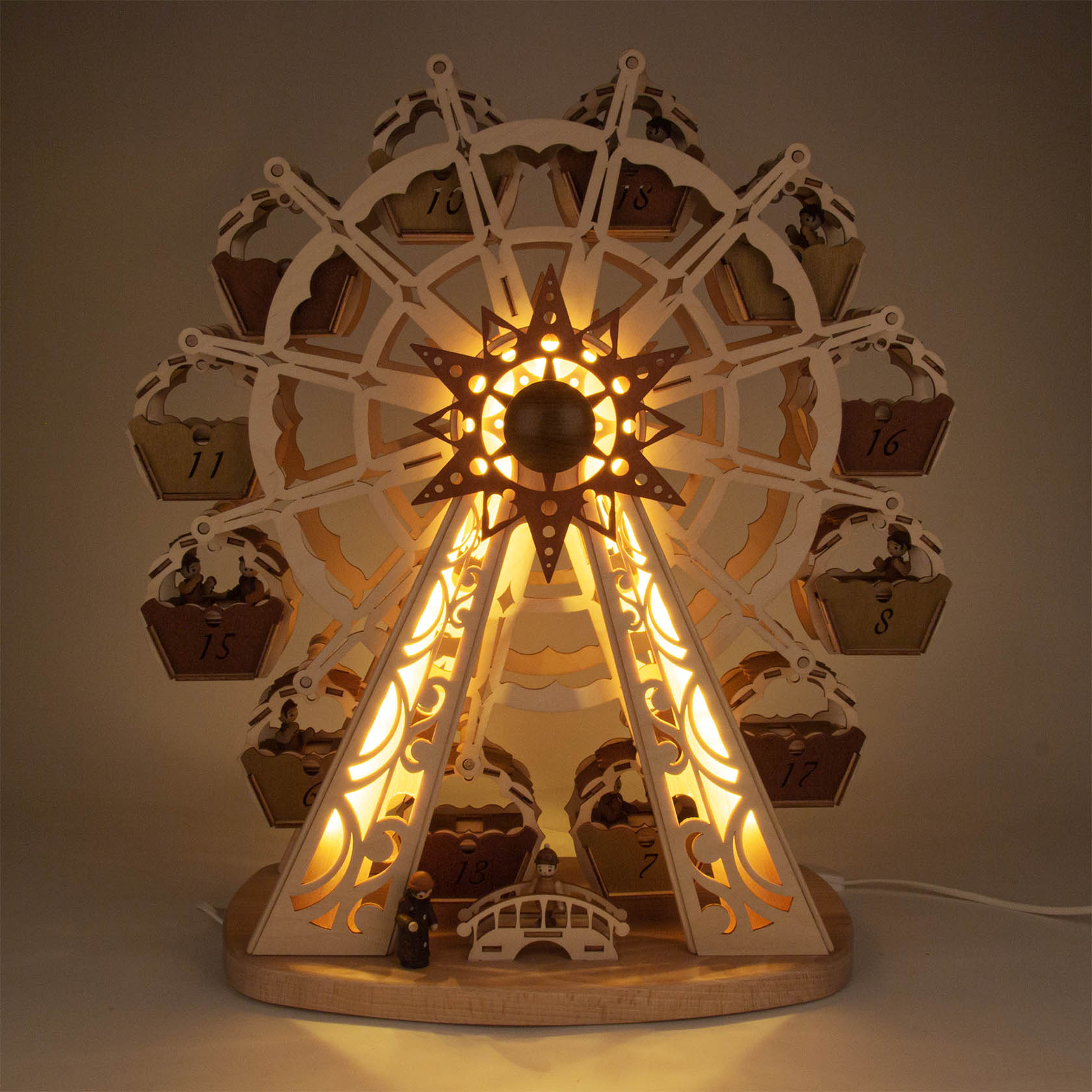 Ein beleuchtetes, manuell drehbares Riesenrad mit 12 Gondeln, die als Adventskalender-Schächtelchen dienen. LED-Licht in der Mitte und an den Stützbalken.