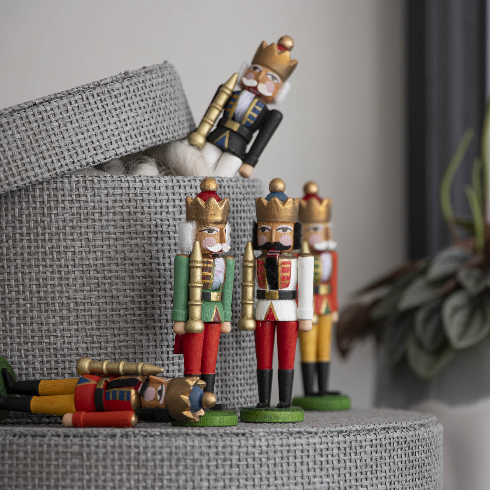 Eine Sammlung von Mini-Nussknacker-Figuren, darunter ein 8 cm großer Nussknacker König in rot-blauer Uniform, steht und liegt dekorativ arrangiert.