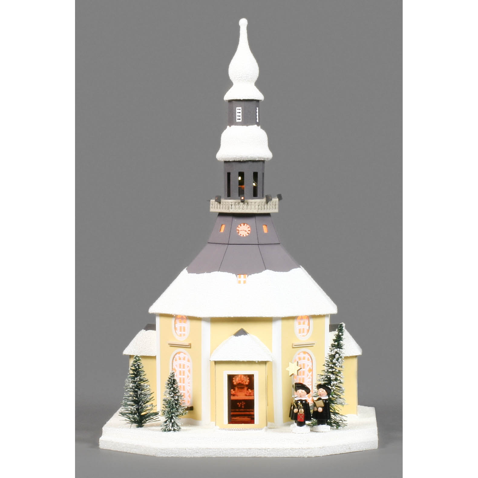 Modell des Seiffener Kirche Lichterhauses mit elektrisch beleuchteten Fenstern und Figuren der Kurrende-Sänger im Vordergrund. Weihnachtsdekoration.