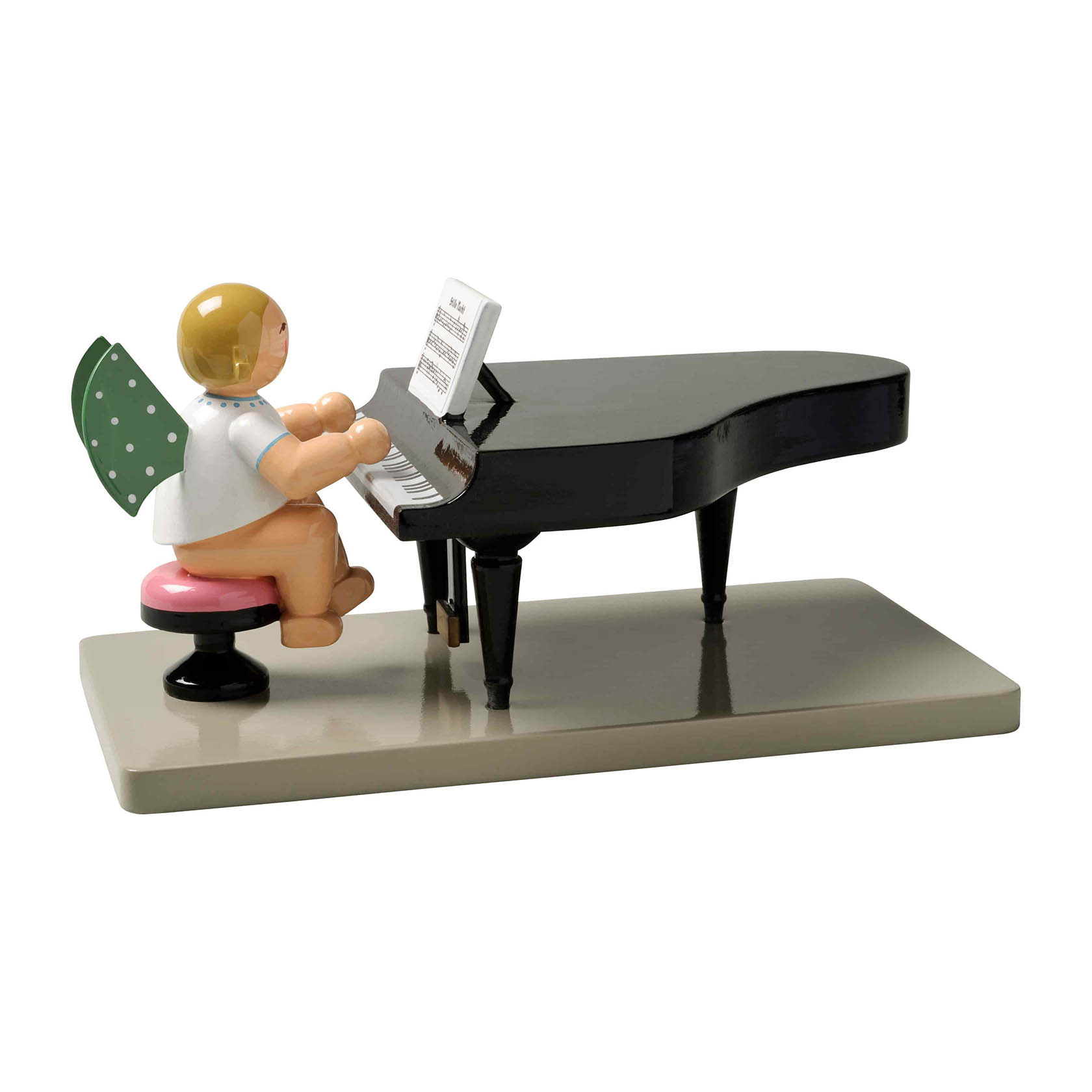 Ein Engel mit grünen Flügeln und weißen Punkten sitzt auf einem Hocker und spielt Klavier auf einem schwarzen Flügel. im Dregeno Online Shop günstig kaufen