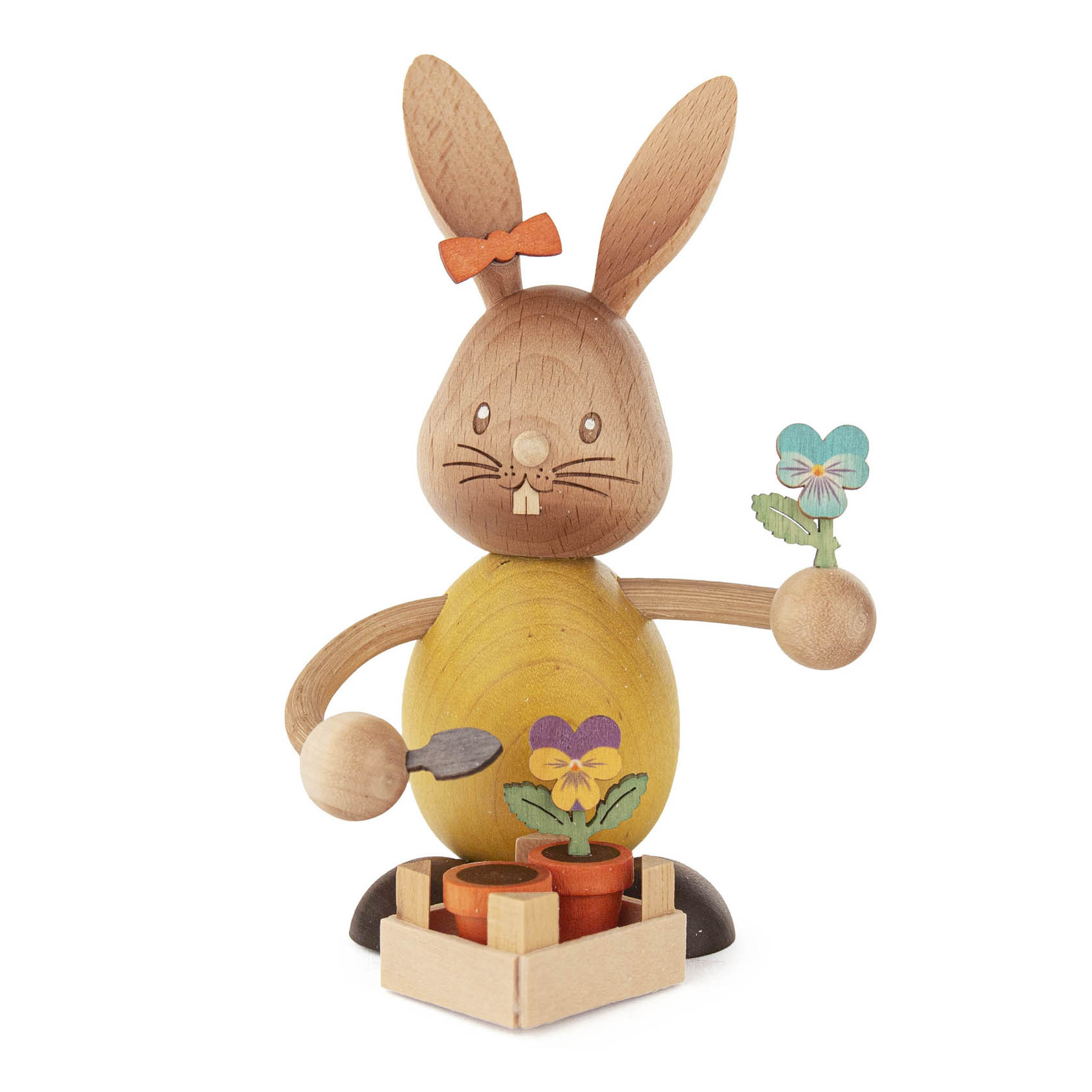 Ein hölzerner Hase namens Stupsi mit einer orangefarbenen Schleife, der Stiefmütterchen in einem Blumenkasten hält. Der Hase hält ein weiteres Stiefmütterchen. im Dregeno Online Shop günstig kaufen