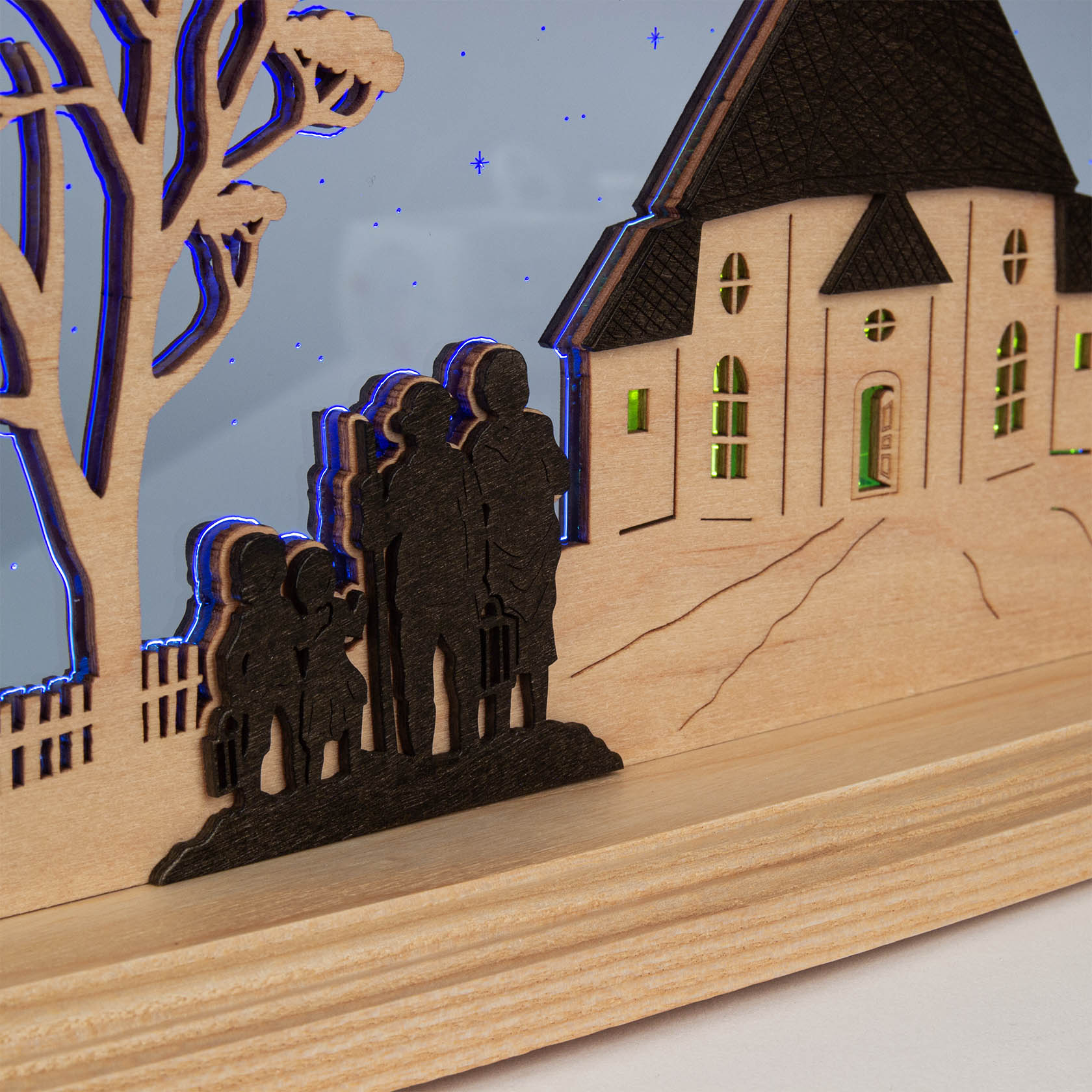Holzleuchte mit der Silhouette der Seiffener Kirche und einer Familie davor in künstlerischer Darstellung.
