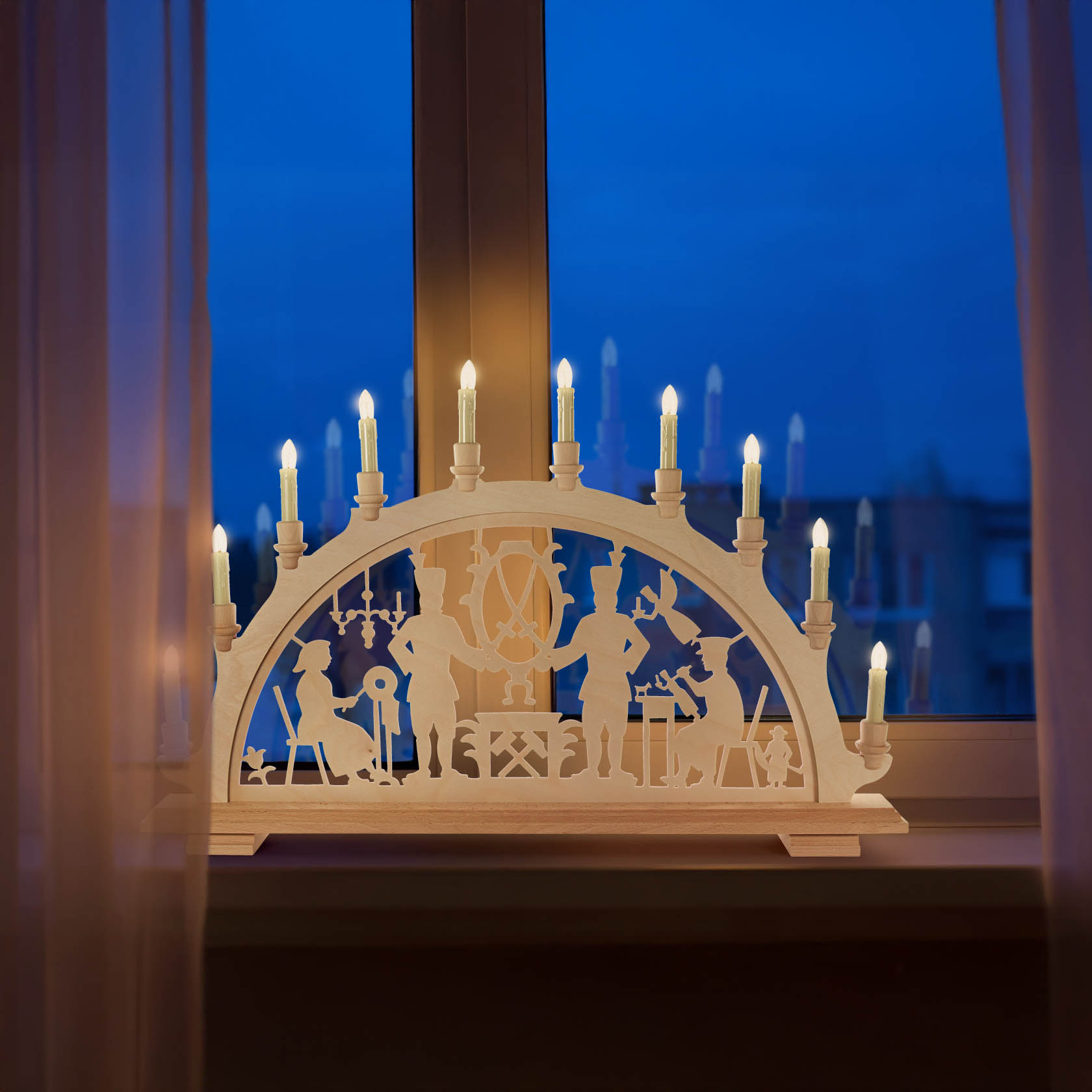 Ein elektrisch beleuchteter Schwibbogen mit Schwarzenberger Motiv an einem Fenster. Silhouetten von Figuren und Szenen sind im Holz geschnitzt.