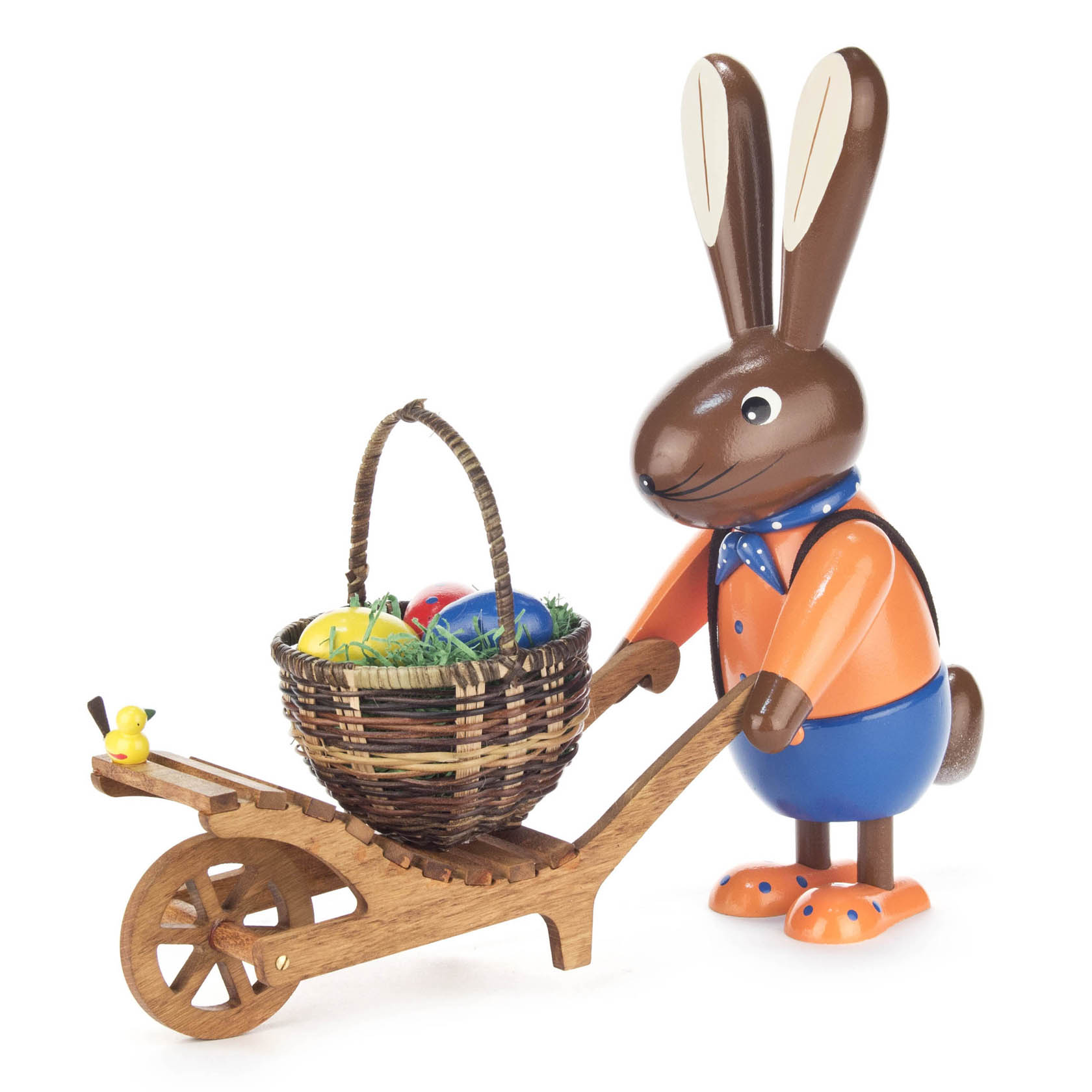 Eine farbige Holzfigur eines Hasen in blauer Hose und orangefarbener Jacke, der eine Schubkarre mit Ostereiern in einem Korb schiebt. im Dregeno Online Shop günstig kaufen