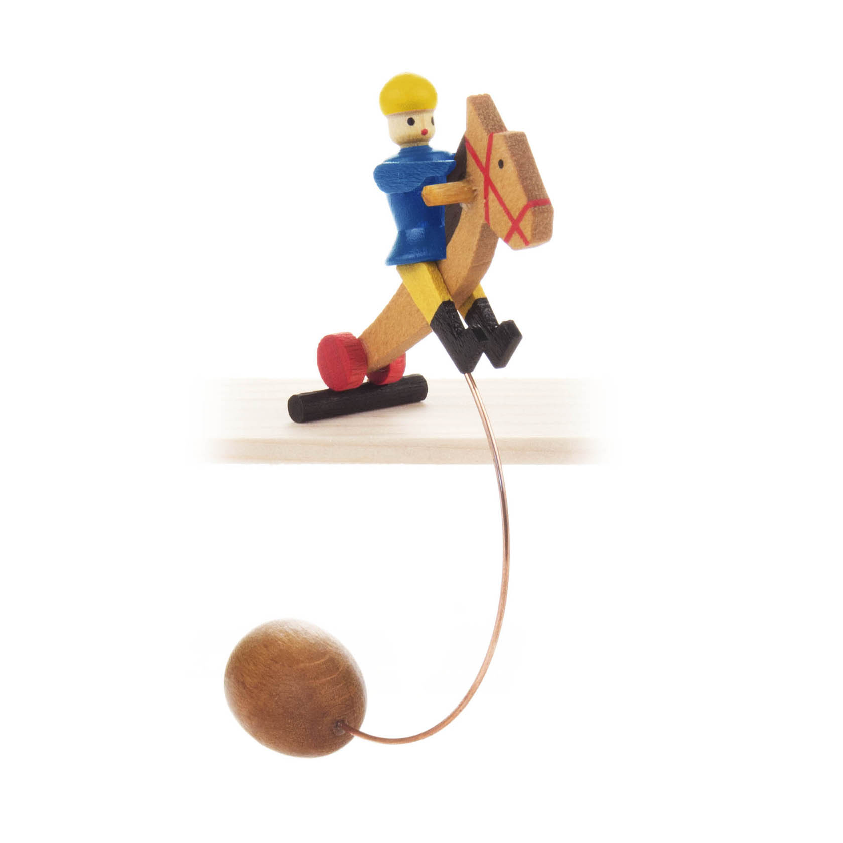 Holzschaukelspielzeug mit einem blauen Reiter auf einem Pferd. Ein langer Draht mit Kugel unten dient als Gewicht. im Dregeno Online Shop günstig kaufen