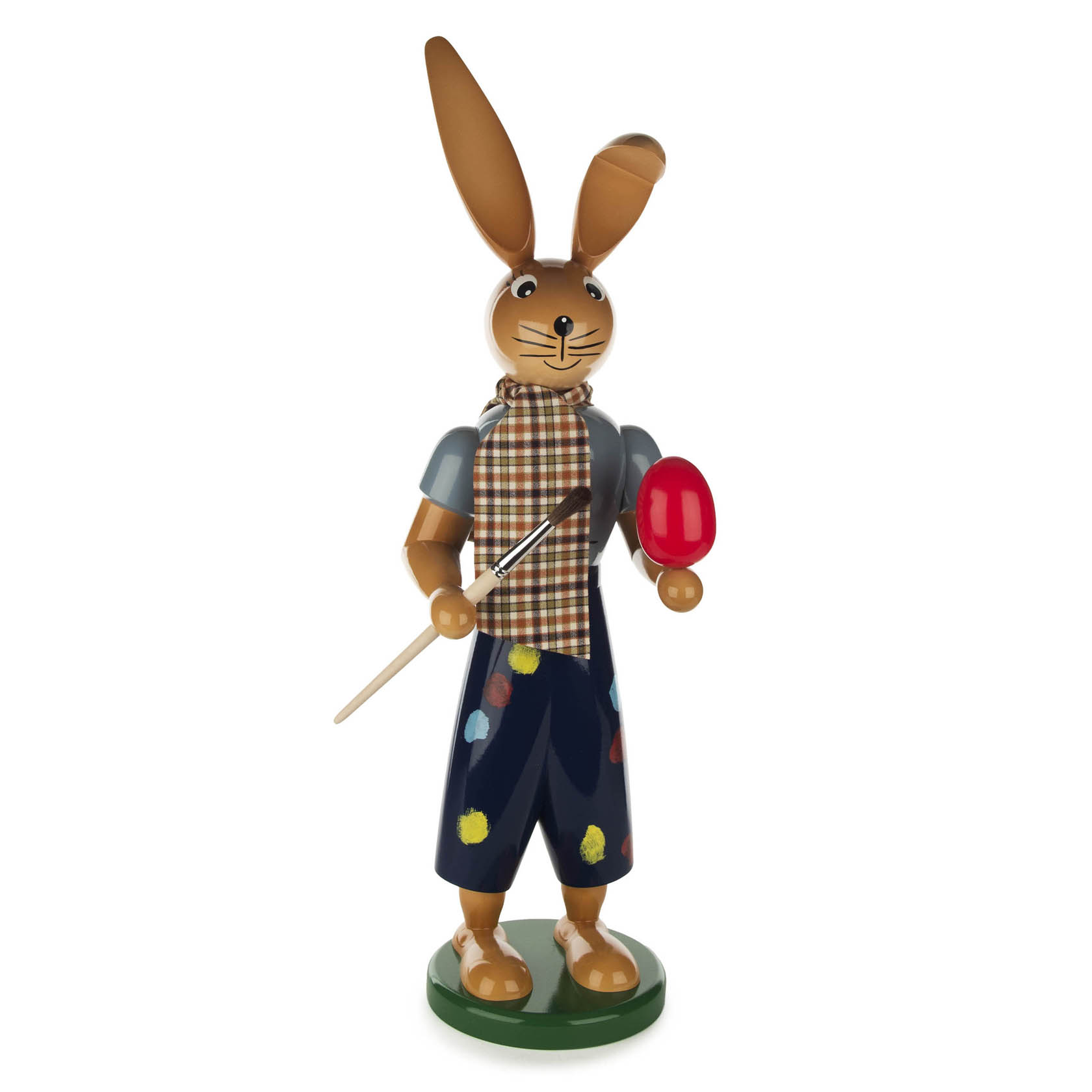 Holzfigur eines Hasen mit gemustertem Schal und Malkittel, hält einen Pinsel in der rechten Pfote und ein rotes Ei in der linken.