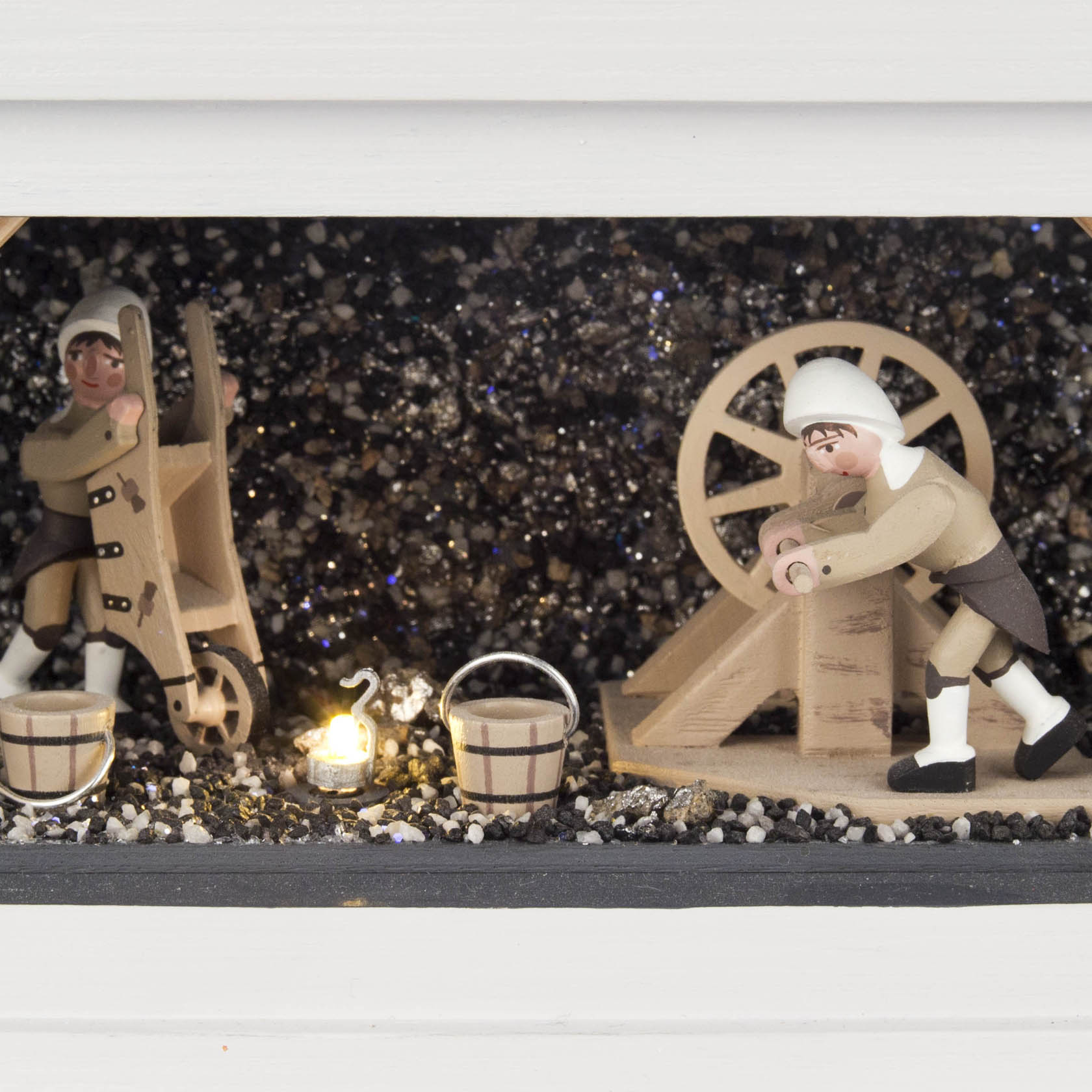 Zwei Holzfiguren in traditioneller Bergmannskleidung neben einem Schaufelrad und Eimern, beleuchtet von elektrischen Lichtern.