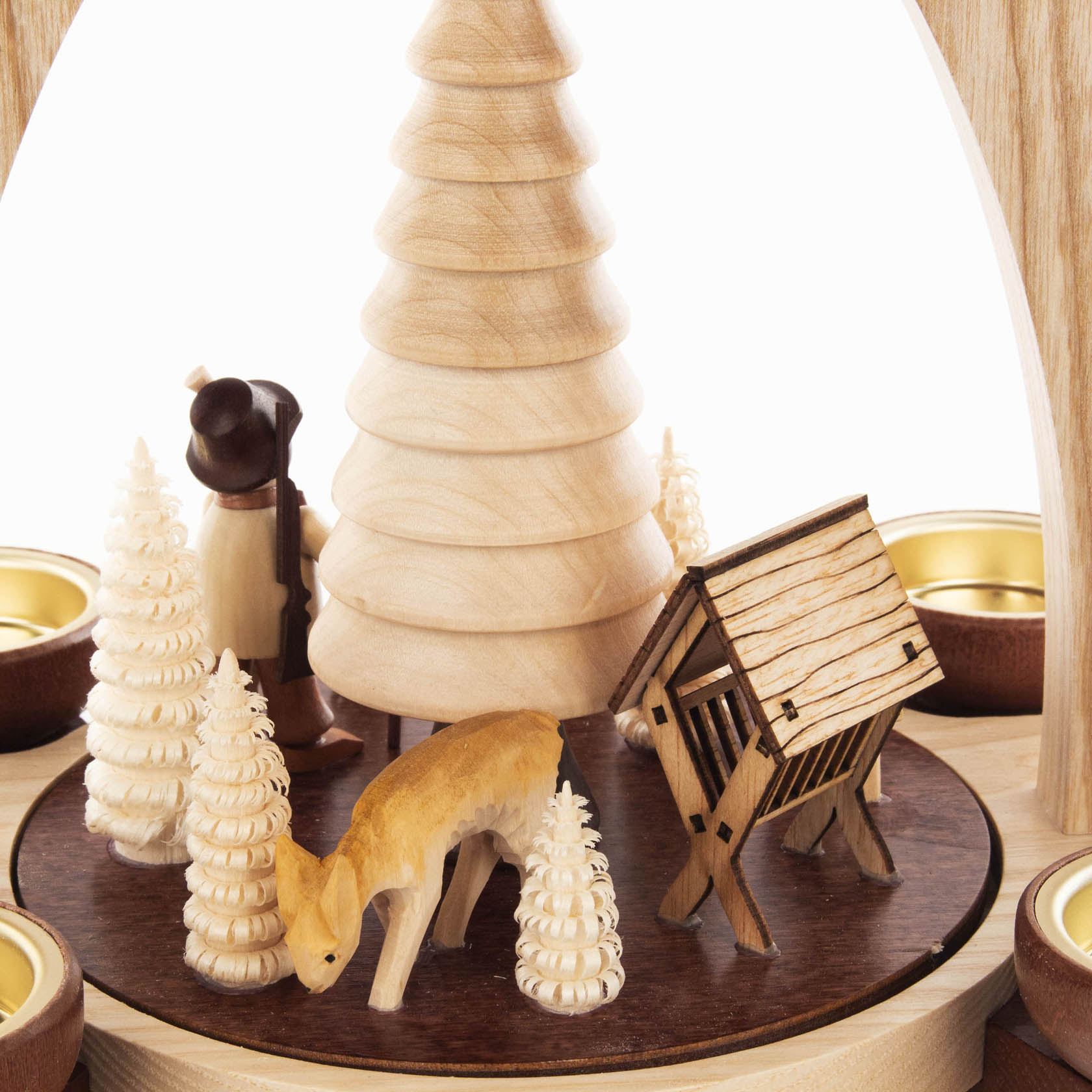 Holzpyramide mit Jägerfigur, Rehen und mehreren kleinen Tannenbäumen, umgeben von Teelichthaltern.
