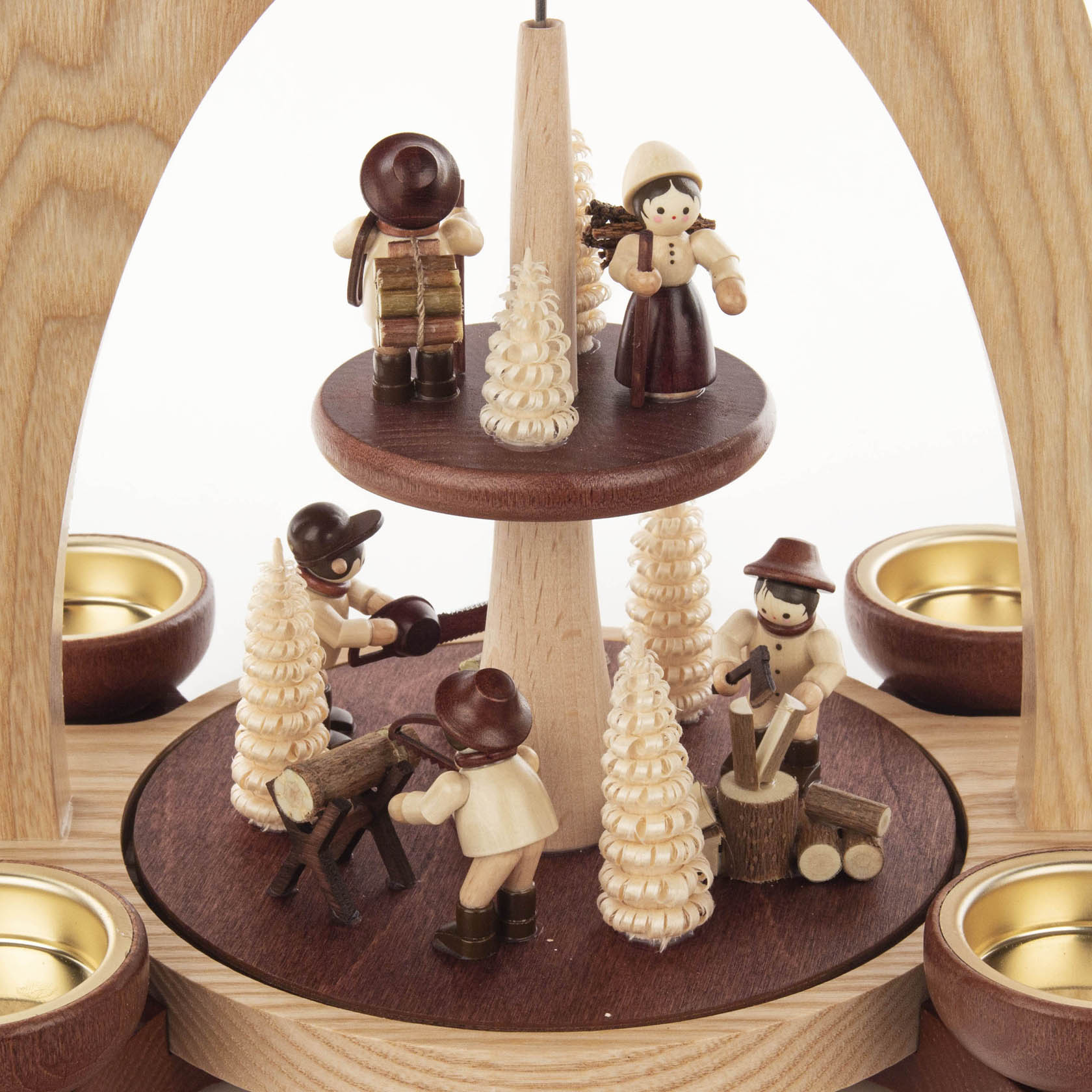 Two-tier wooden pyramid with forest motif, featuring small figurines doing lumberjack activities, surrounded by miniature trees and tea light holders.