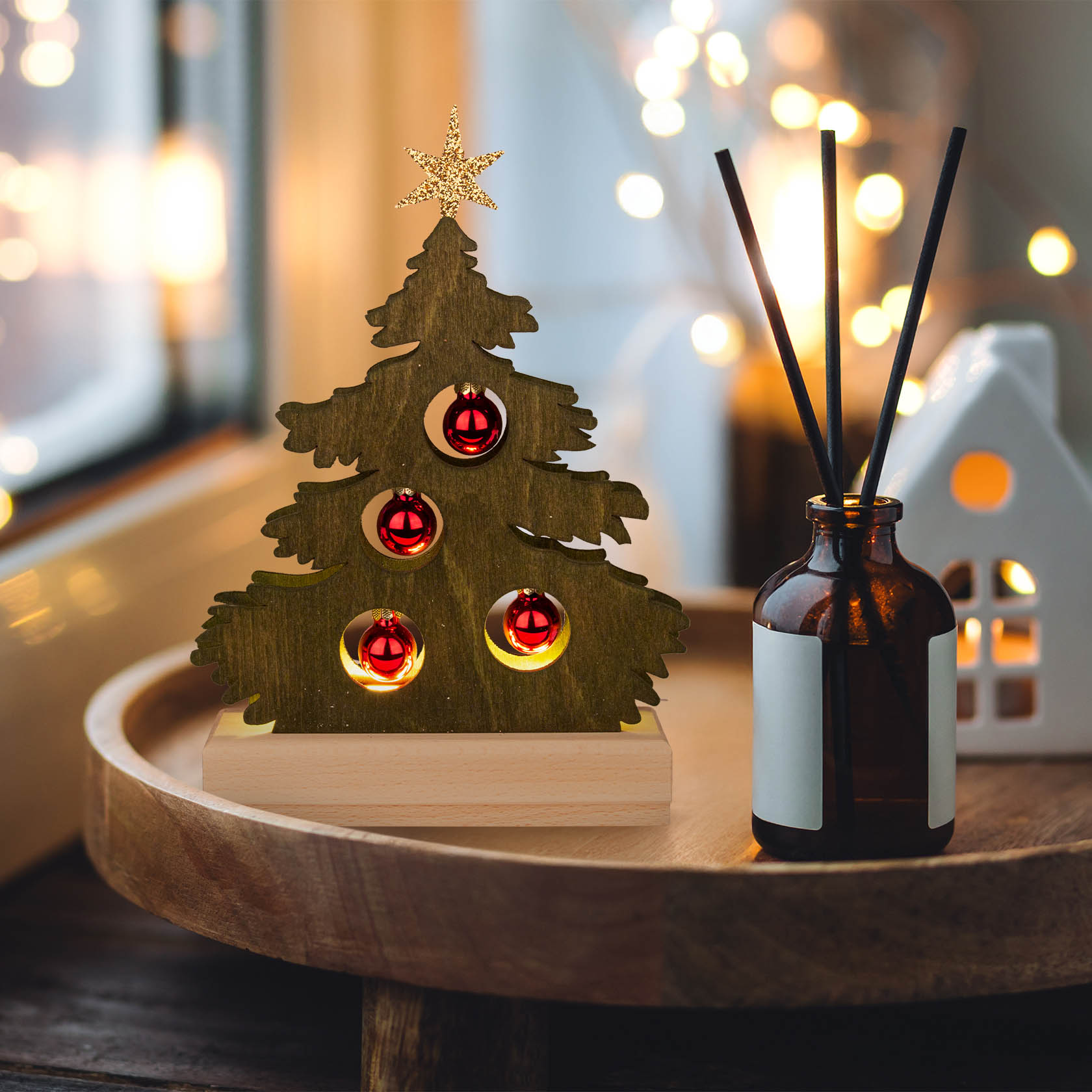 Grüne Mini-Tanne aus Holz mit roten Kugeln und LED-Strip Beleuchtung auf einem Tisch, dekoriert für die Weihnachtszeit.