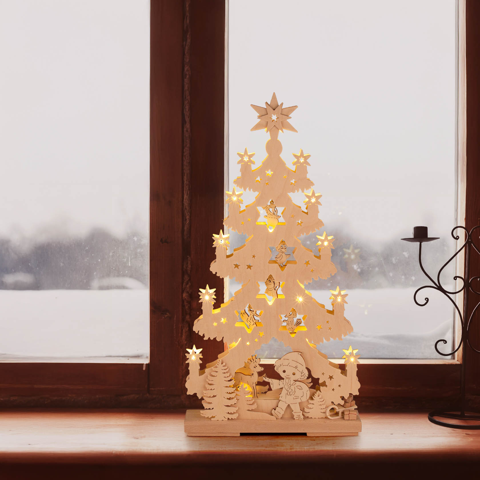 Wooden Christmas tree with LED lights, featuring Sandman figure in a fairytale forest setting, placed on a window sill.