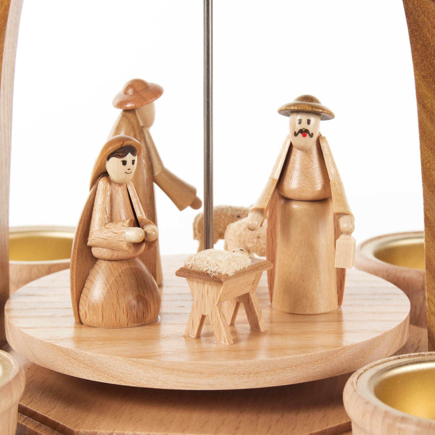 Wooden Christmas pyramid with nativity scene, featuring wooden figures of Mary, Joseph, and baby Jesus in a manger, surrounded by candle holders.