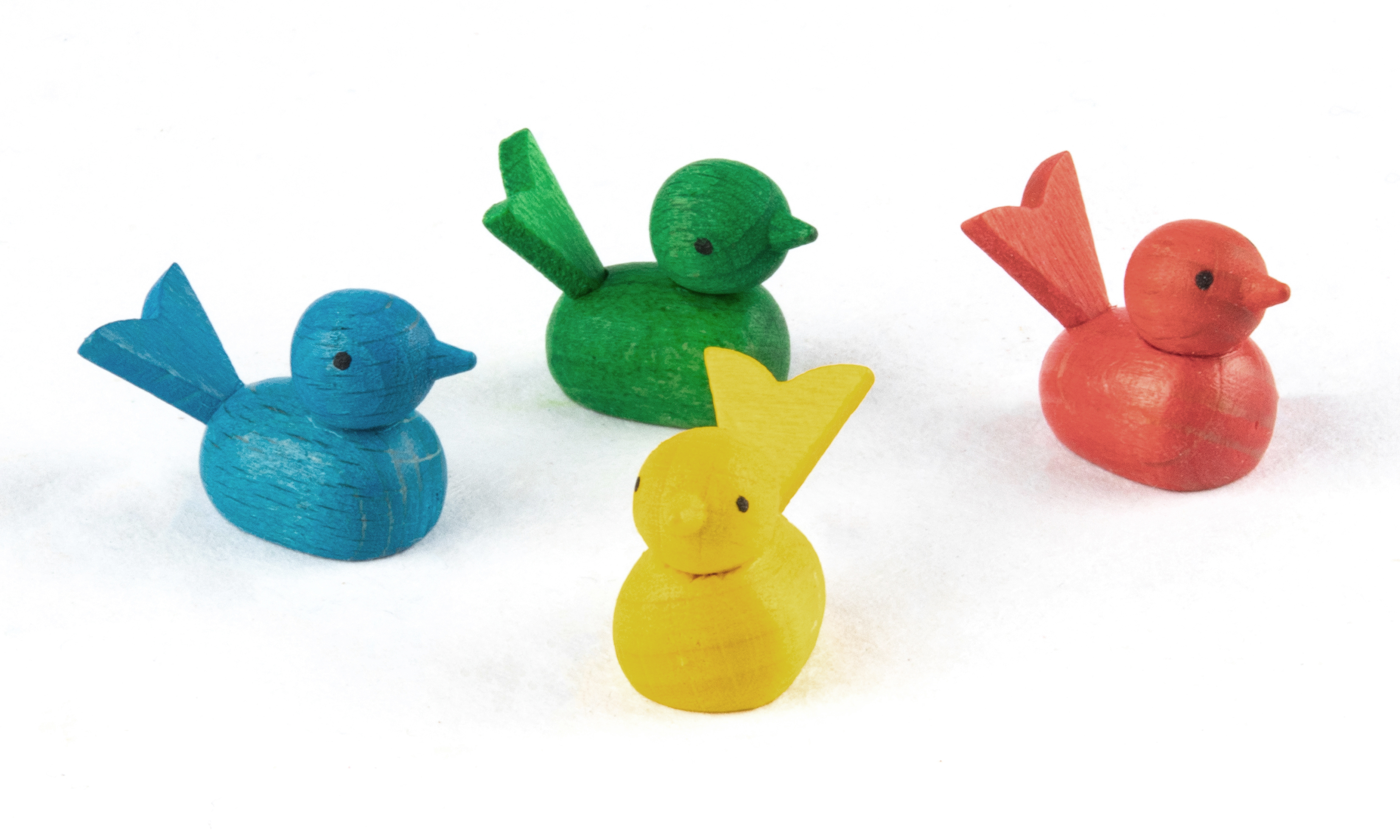 Four small, colorful wooden bird figures: one yellow in the front, with a green, a red, and a blue bird in the background. im Dregeno Online Shop günstig kaufen