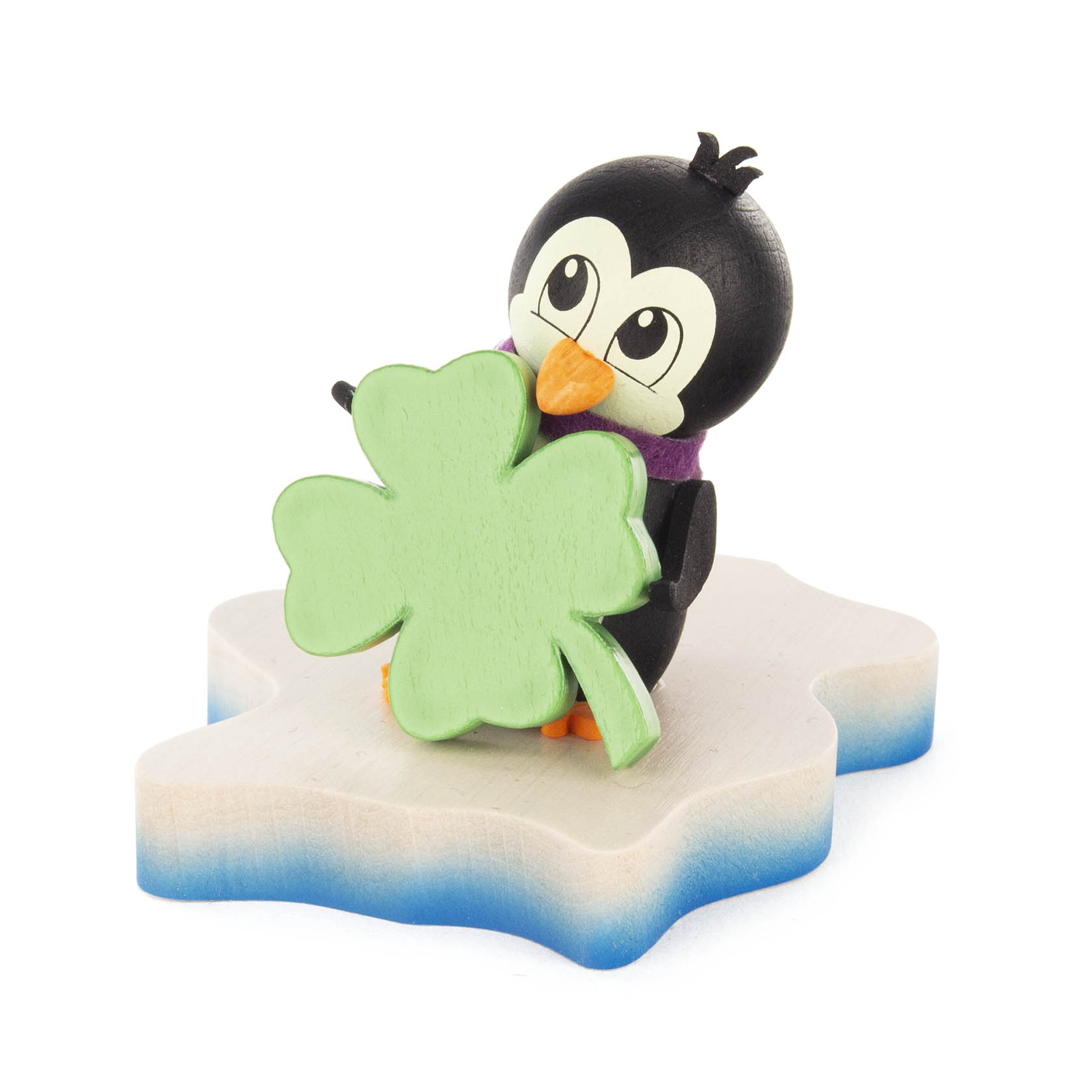 A cute wooden penguin figurine standing on an ice floe holding a large green four-leaf clover. im Dregeno Online Shop günstig kaufen