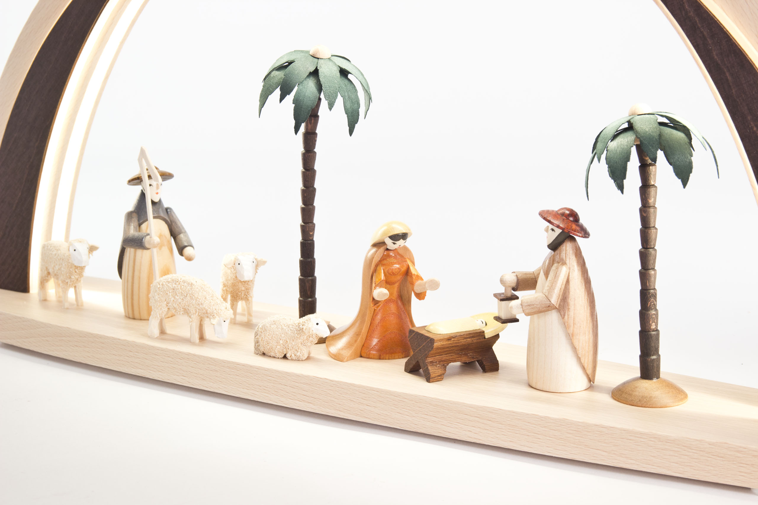 Schwibbogen-Darstellung der Geburt Christi mit handgefertigten Figuren. Maria, Josef, Jesus in der Krippe sowie Hirten, Schafe und Palmen, indirekt beleuchtet.