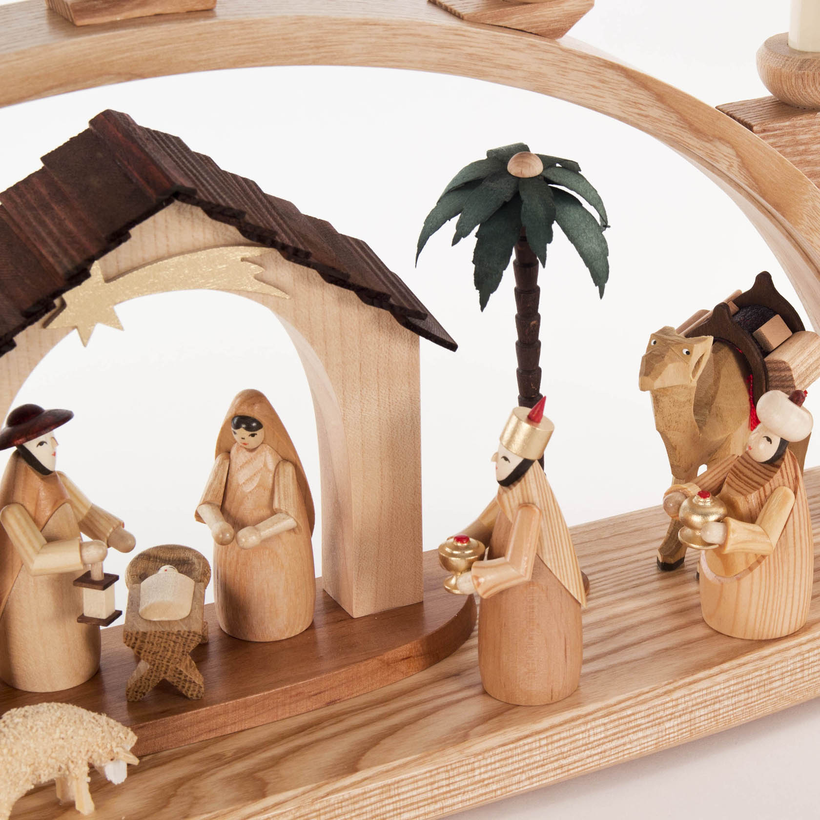 Ein naturbelassener Schwibbogen zeigt die Szene der Geburt Christi. Maria und Josef knien neben der Krippe, während die Heiligen Drei Könige mit Geschenken kommen.