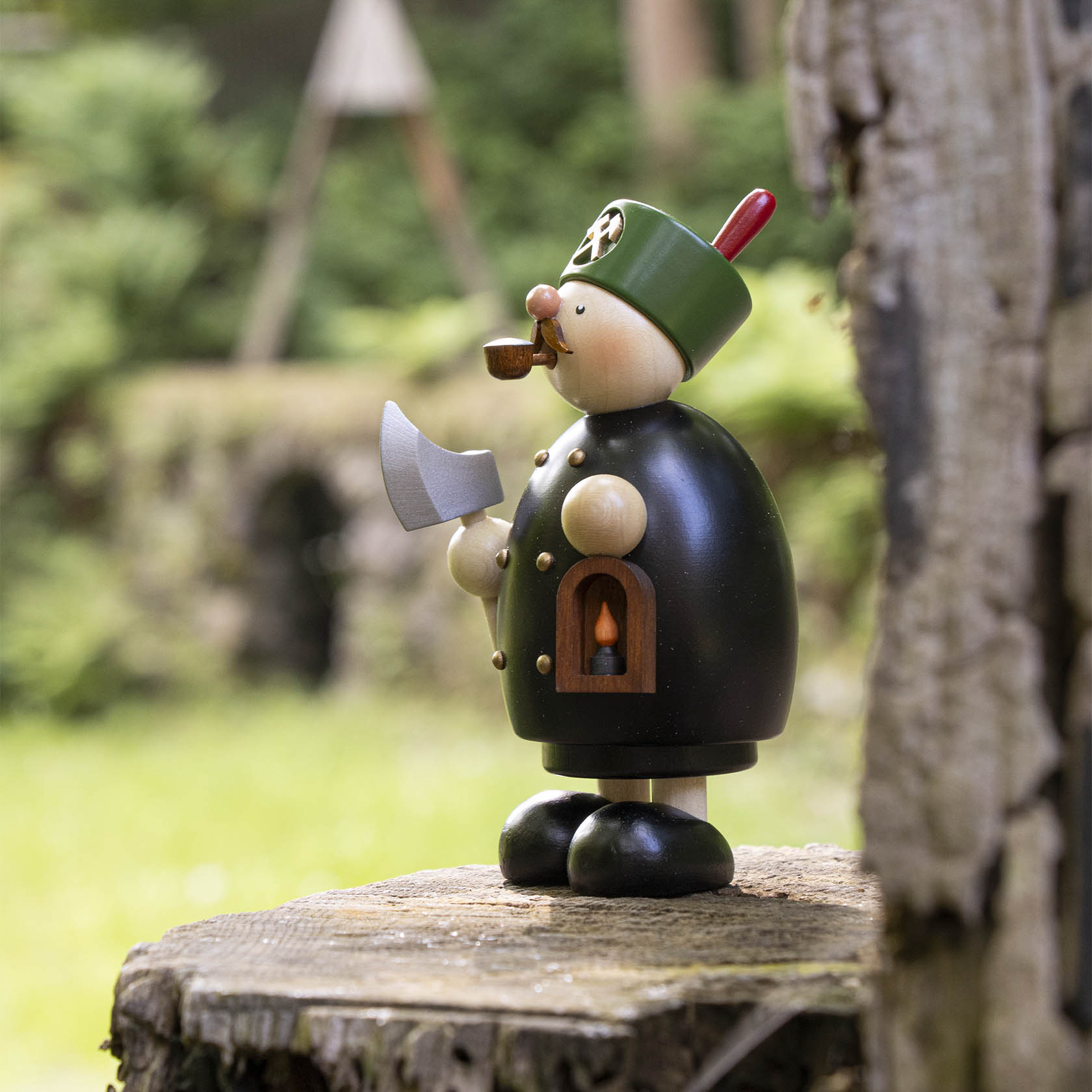 A traditional German wooden incense smoker shaped like a miner, featuring a green hat, black body, gold buttons, and holding a pickaxe, with smoke coming from a pipe.