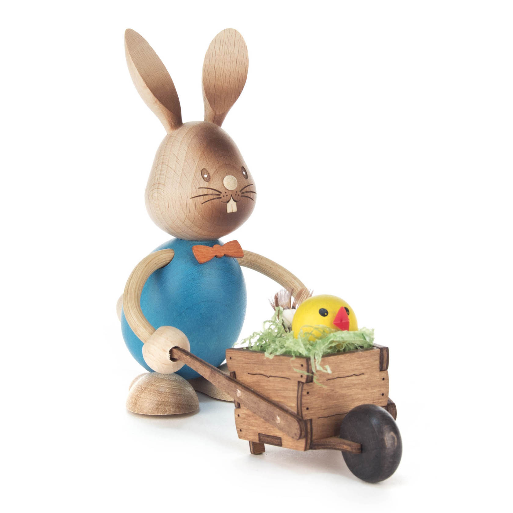 Holzhase Stupsi in blauem Outfit mit orangefarbener Fliege schiebt kleine Holzschubkarre mit gelbem Küken und Gras. im Dregeno Online Shop günstig kaufen