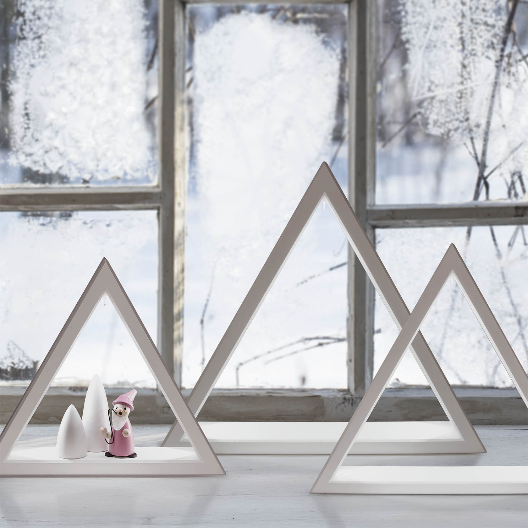 Beleuchtetes weißes Dreieck aus Holz mit LED-Streifen und pinken Figuren im Inneren, auf einem Holzboden platziert.
