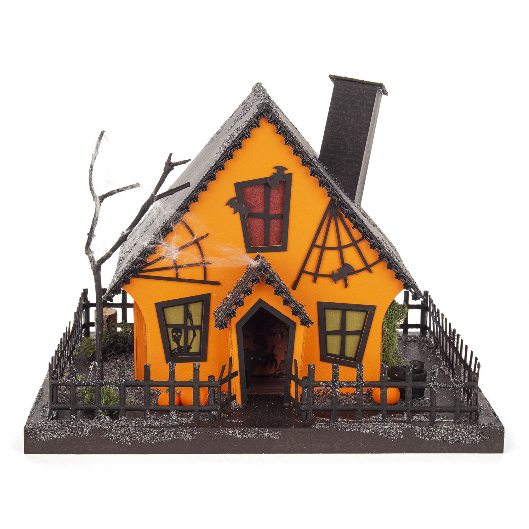 Ein dekoratives Lichterhaus in Form eines Kürbishaus mit orangefarbener Fassade, spitzem Dach, verzierten Fenstern und einem kahlen Baum daneben. im Dregeno Online Shop günstig kaufen