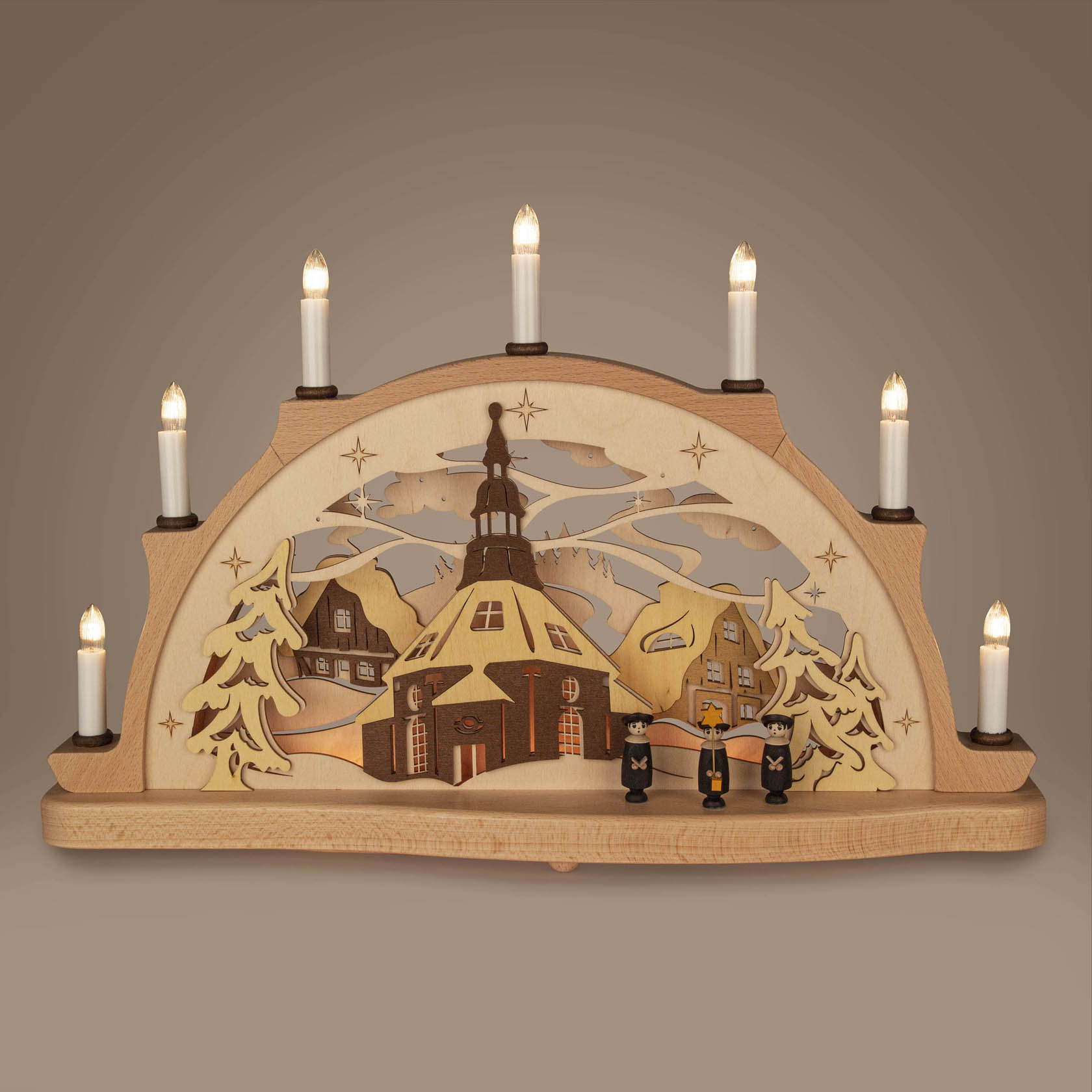 Holzschwibbogen mit Seiffener Kirche, elektrischen Kerzen und 3D-Schnitzerei von Häusern und Bäumen. Figuren vor der Kirche stehen auf dem Bogen.