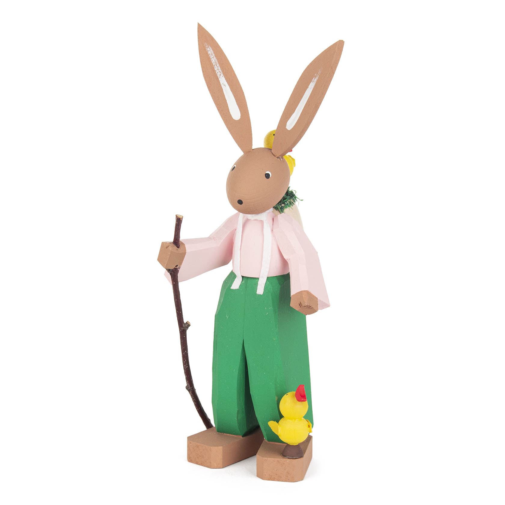 Holzfigur eines Osterhasen namens Hugo in grüner Hose und pinkem Hemd, hält einen Stock und hat gelbe Kükenfiguren an seinen Füßen.