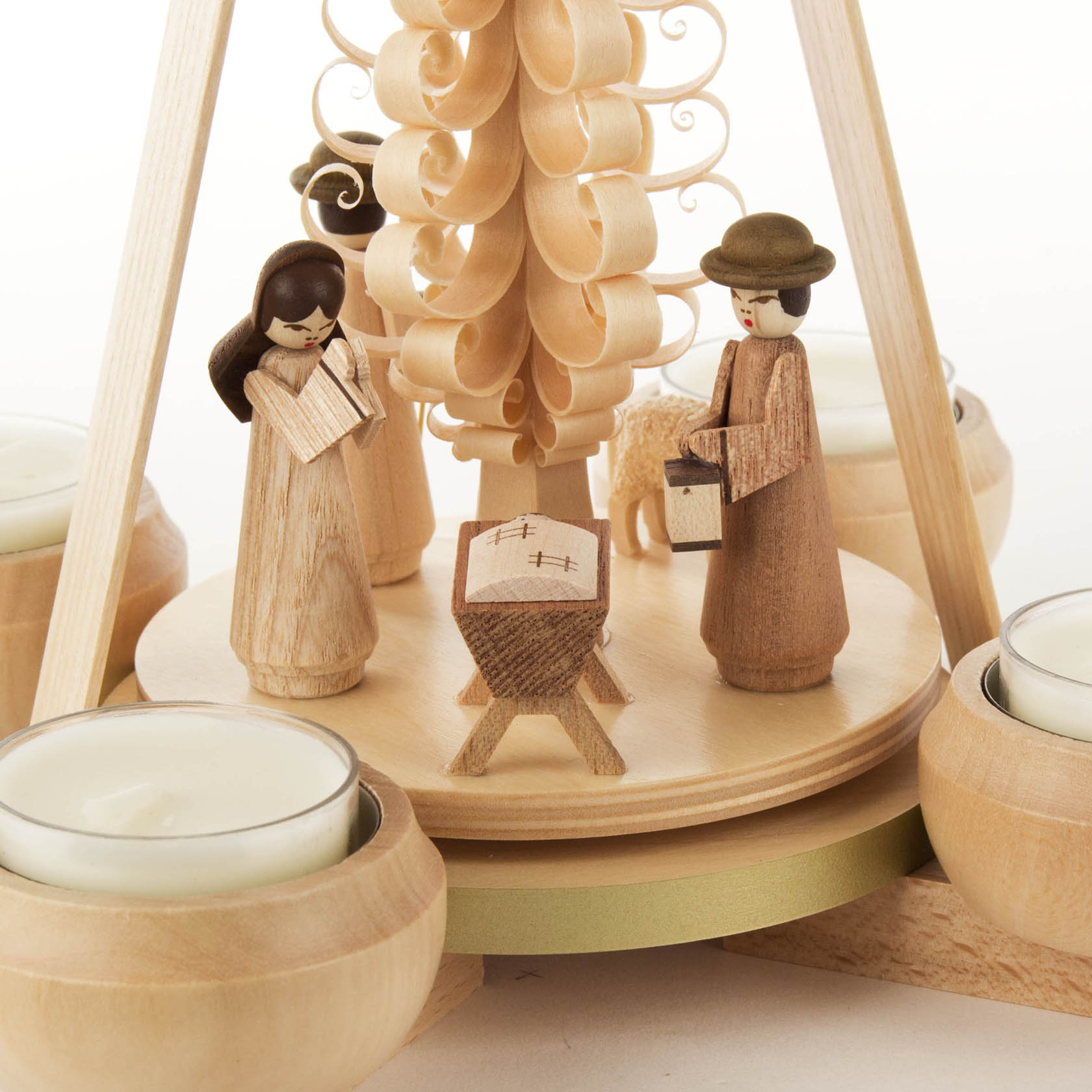 Eine hölzerne Weihnachtspyramide mit Figuren der Weihnachtsgeschichte: Maria, Josef und das Jesuskind in der Krippe, umgeben von Teelichthaltern.