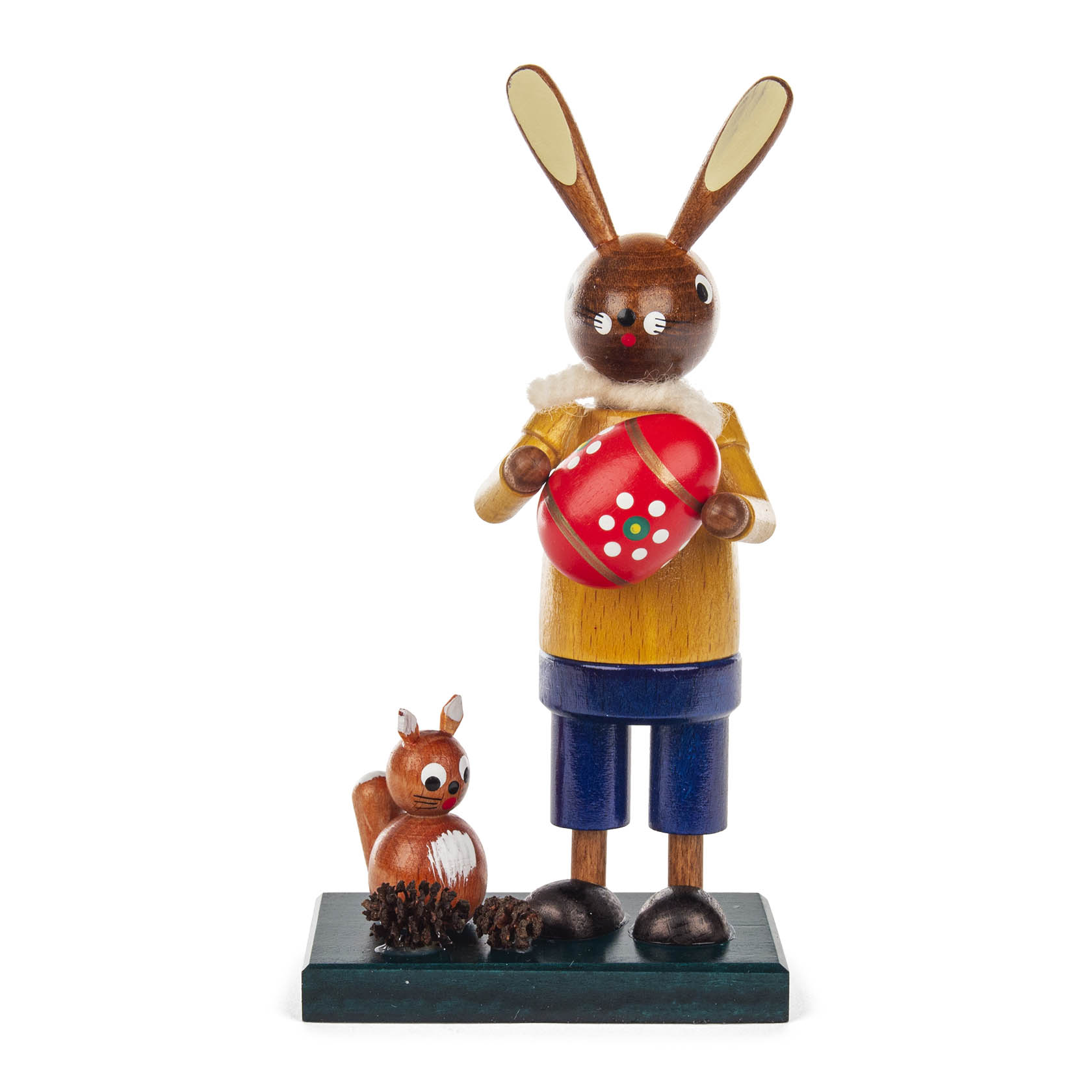 Holzfigur eines Osterhasen in gelber Jacke, der ein rotes Ei mit weißen Punkten hält. Neben ihm steht ein kleines Eichhörnchen auf grüner Basis. im Dregeno Online Shop günstig kaufen