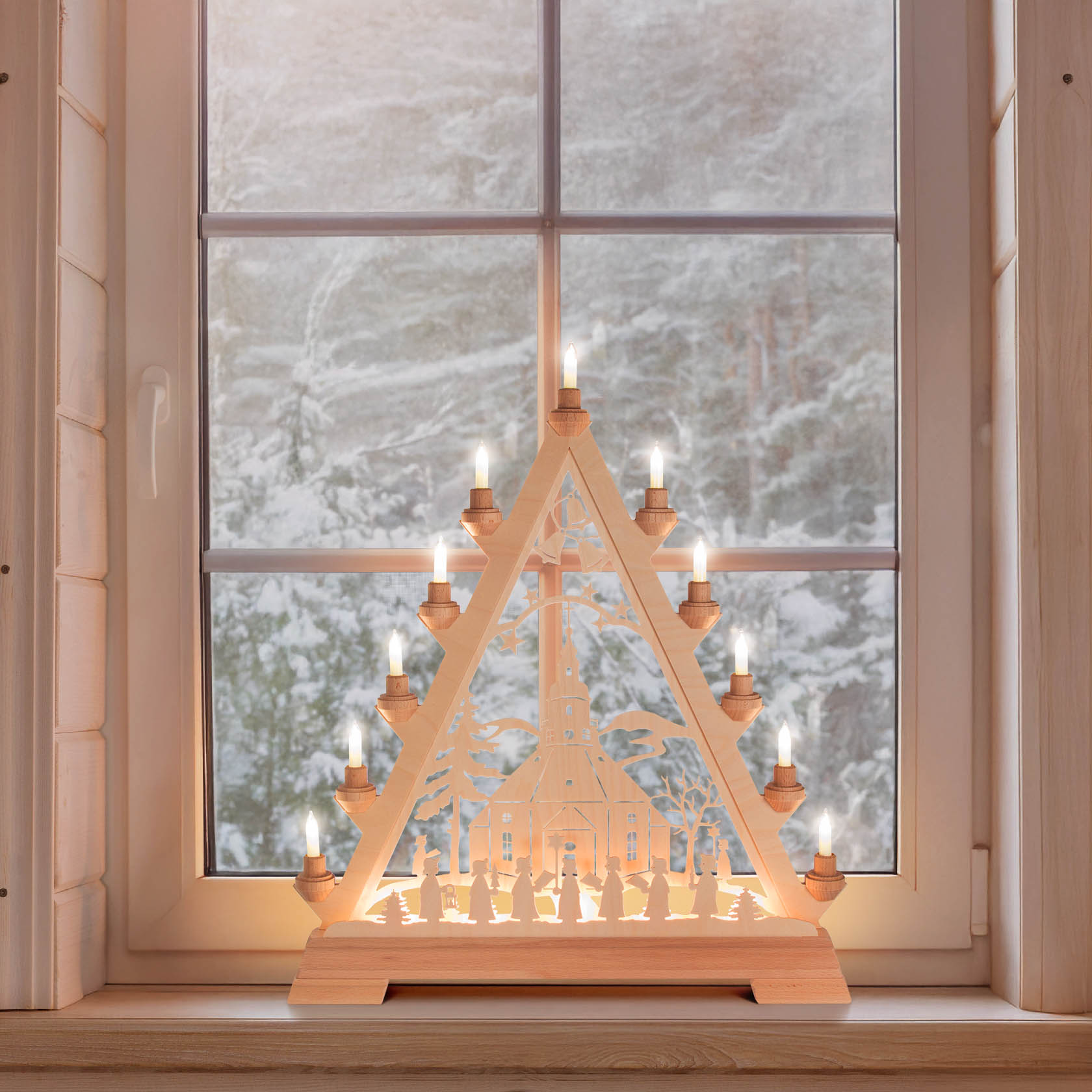 Ein beleuchtetes Holz-Weihnachtsdreieck zeigt die Seiffener Kirche im Zentrum und eine Kurrende, mit elektrischen Kerzen an den Kanten auf einer Fensterbank.