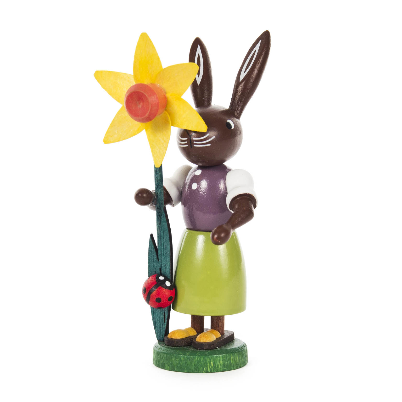 Holzfigur einer Häsin mit braunem Fell und auffälligen langen Ohren. Sie trägt ein lila Oberteil und einen grünen Rock und hält eine große gelbe Narzisse. im Dregeno Online Shop günstig kaufen
