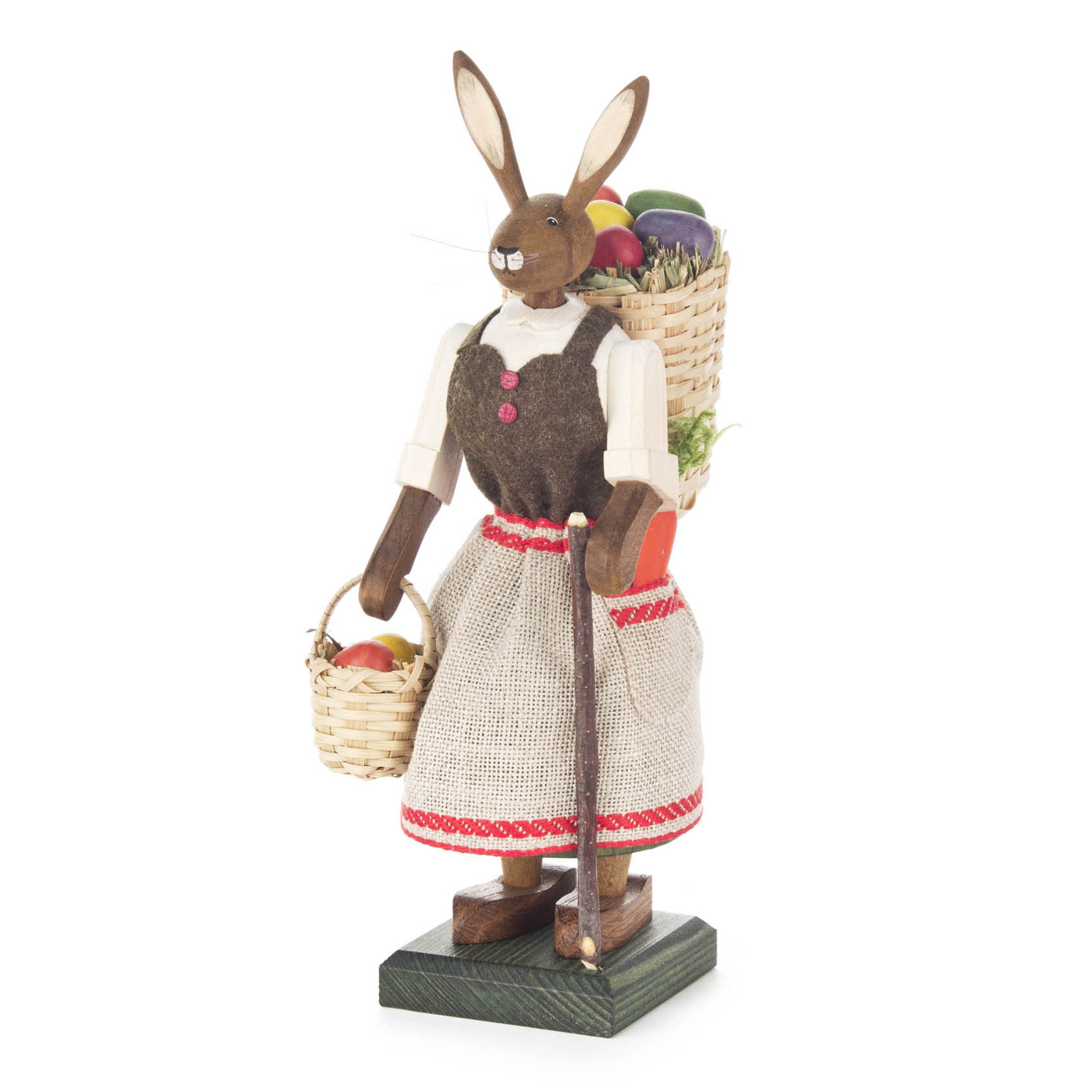 Holzfigur einer weiblichen Hasenfigur in traditioneller Kleidung. Sie hält einen Korb mit roten Eiern und trägt einen Rucksack voller Gemüse. im Dregeno Online Shop günstig kaufen