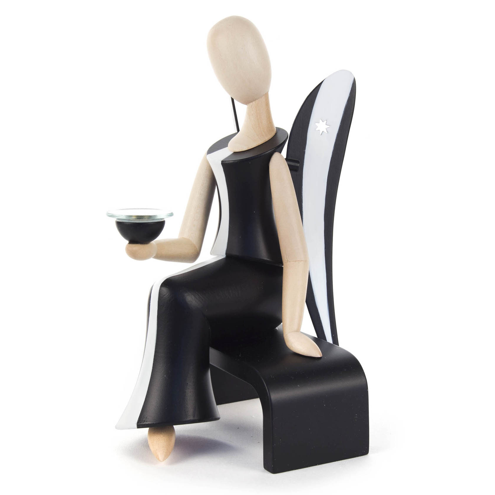 Holzfigur eines Engels mit schwarzem Kleid und weißem Stern auf dem Kopf, hält einen Kerzenhalter. Die Figur sitzt und ist 15,5 cm groß. im Dregeno Online Shop günstig kaufen
