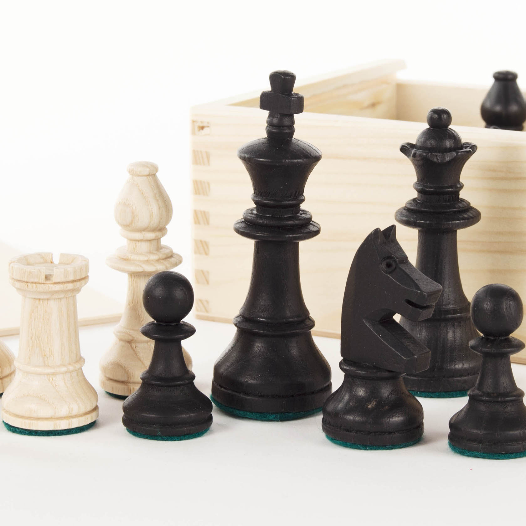 Ein Set von schwarz-weißen Schachfiguren, darunter König, Dame, Turm, Springer, Läufer und Bauern, stehen vor einer offenen Holzschachtel.