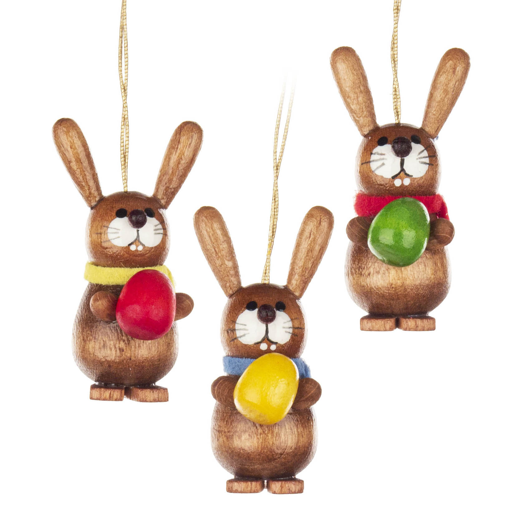 Drei Holzosterhasen als Dekoanhänger, jeder Hase hält ein buntes Ei: rot, gelb und grün, und trägt Schals in verschiedenen Farben. im Dregeno Online Shop günstig kaufen