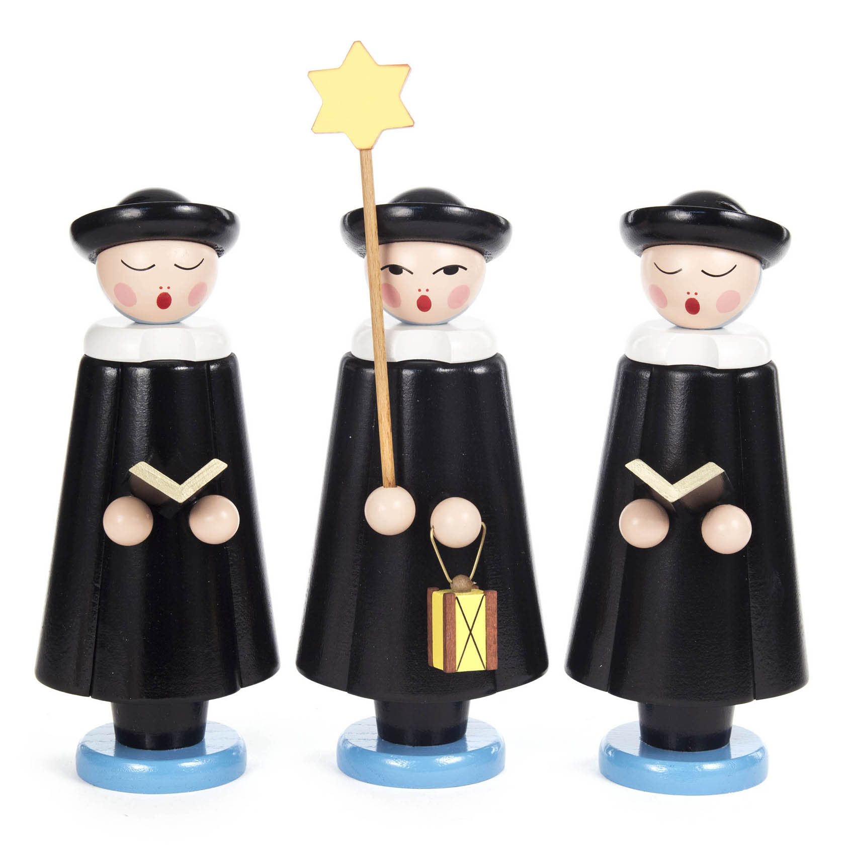 Drei Kurrendefiguren in schwarzer Kleidung, zwei halten ein Buch und eine eine Laterne mit Stern, alle tragen Hüte und haben rosige Wangen. im Dregeno Online Shop günstig kaufen