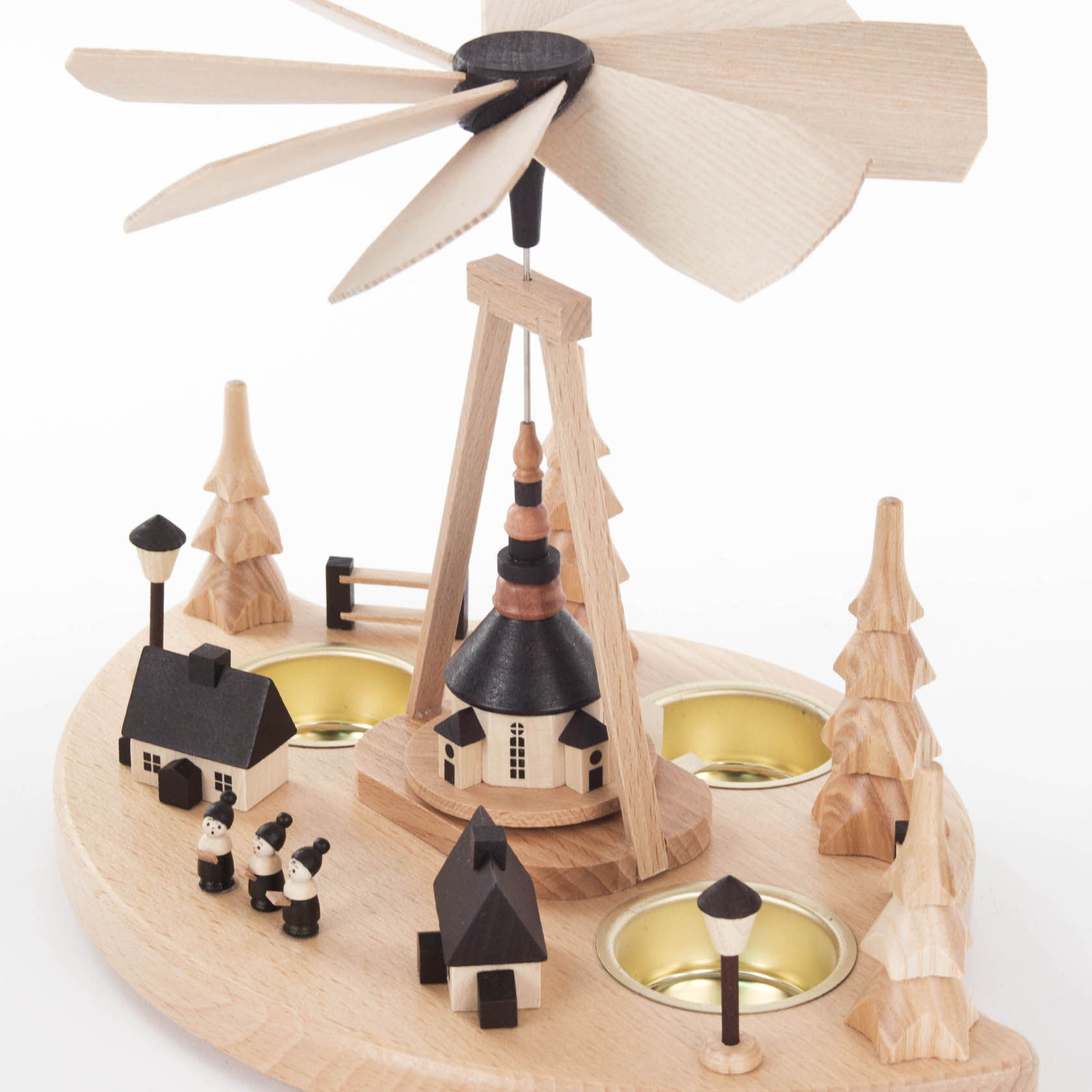 Holz-Weihnachtsberg mit kleiner Kirche, umgeben von Bäumen, zwei Figuren und drei Teelichthaltern. Oben eine sich drehende Holzflügelpyramide.
