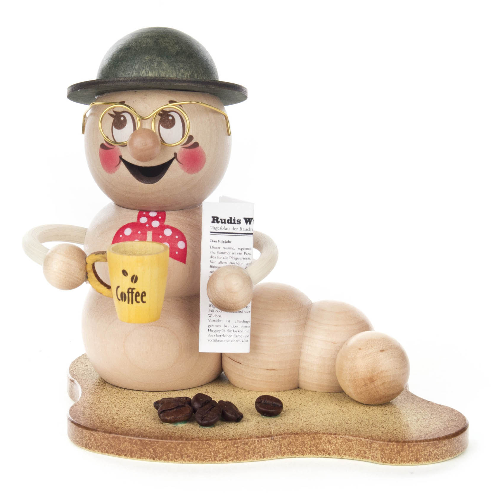 Holzwurmfigur mit Brille, rotem Halstuch, Kaffeetasse und Hut hält eine Zeitung. Drei kleine braune Bohnen liegen auf dem Boden. im Dregeno Online Shop günstig kaufen