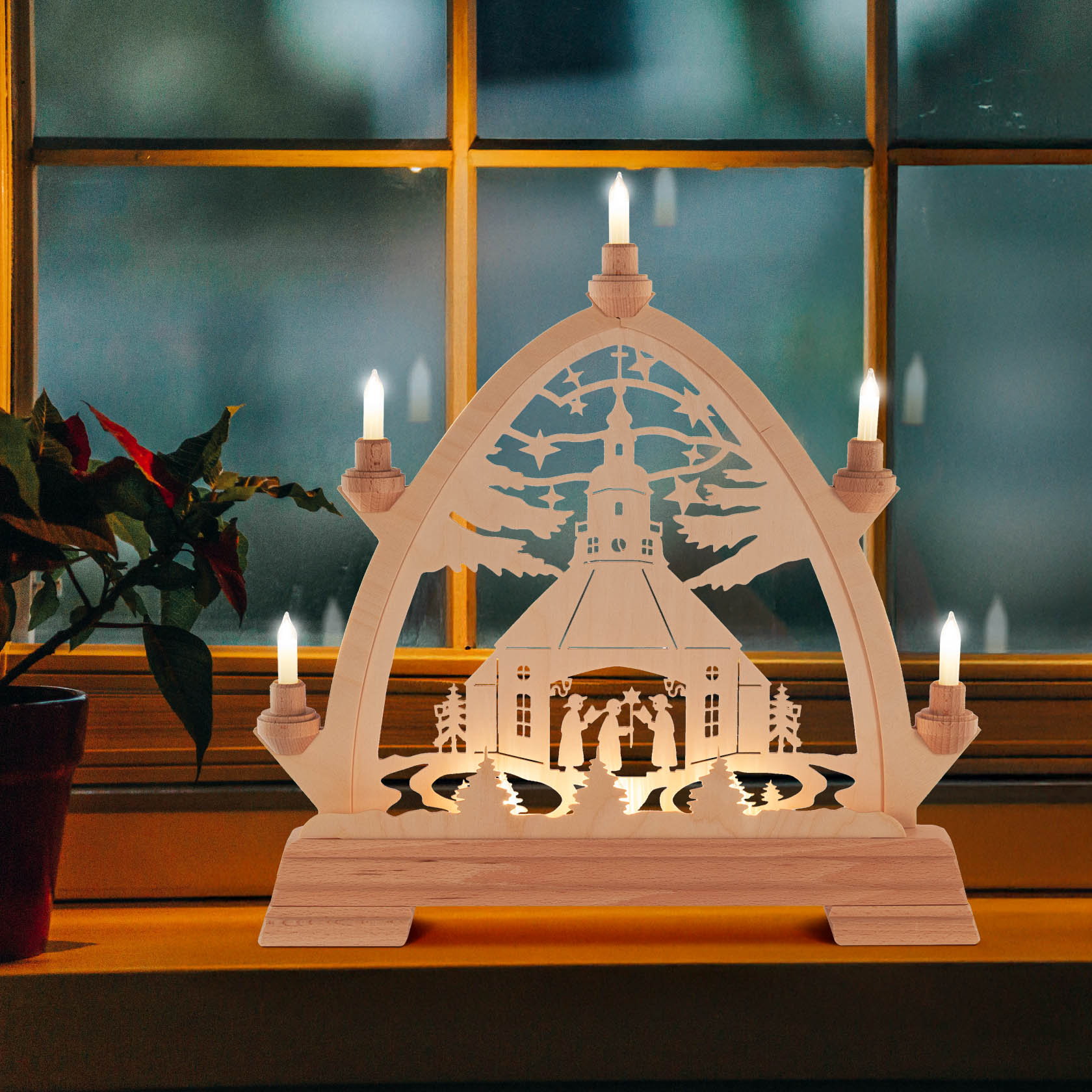 Ein Weihnachtsschwibbogen mit gotischem Bogen zeigt die Seiffener Kirche und Kurrendesänger, elektrisch beleuchtet mit fünf Kerzen.