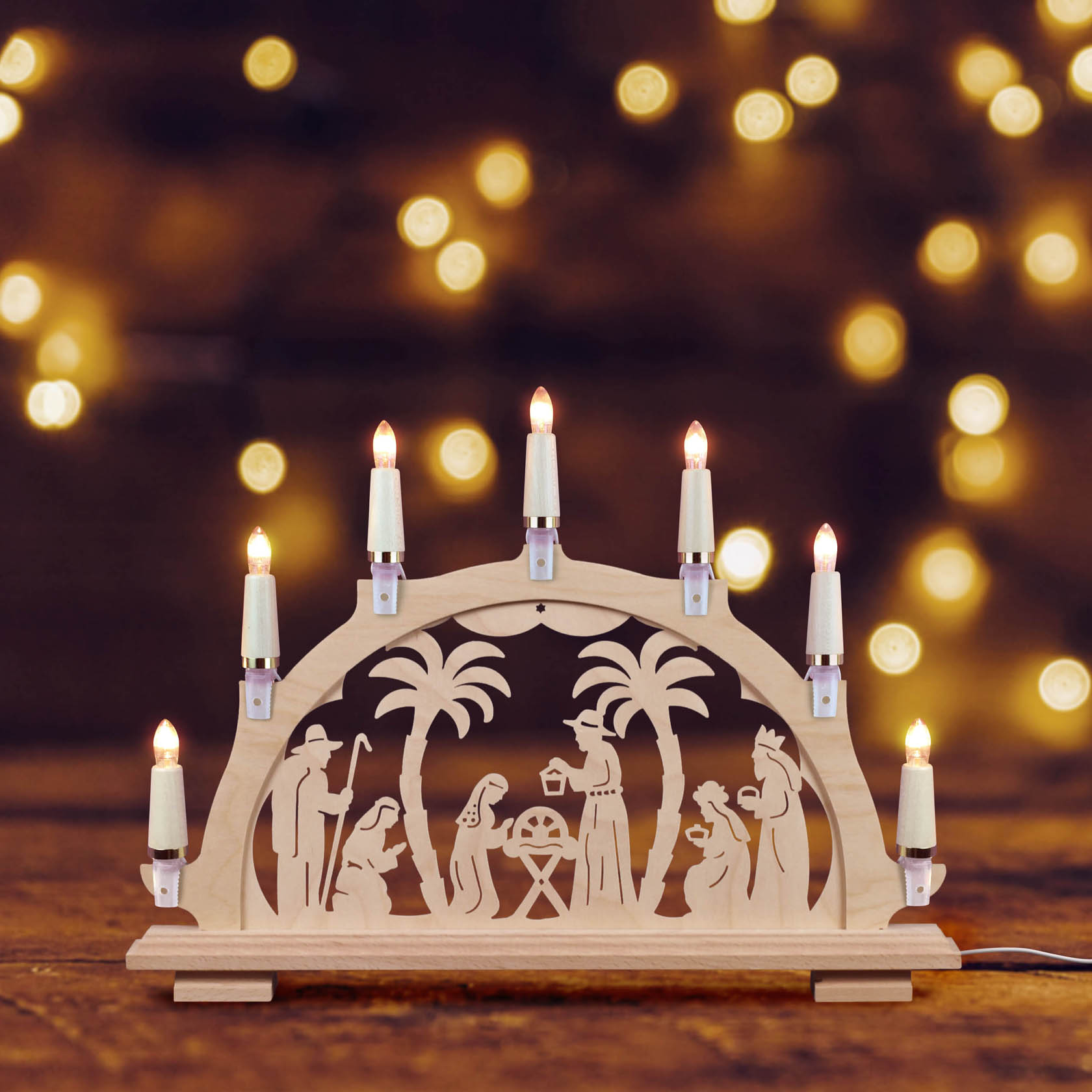 Schwibbogenkette mit sieben Lichtern, gefertigt aus Holz, zeigt ein geschnitztes Weihnachtsszenario mit der Geburt Jesu unter Palmen.