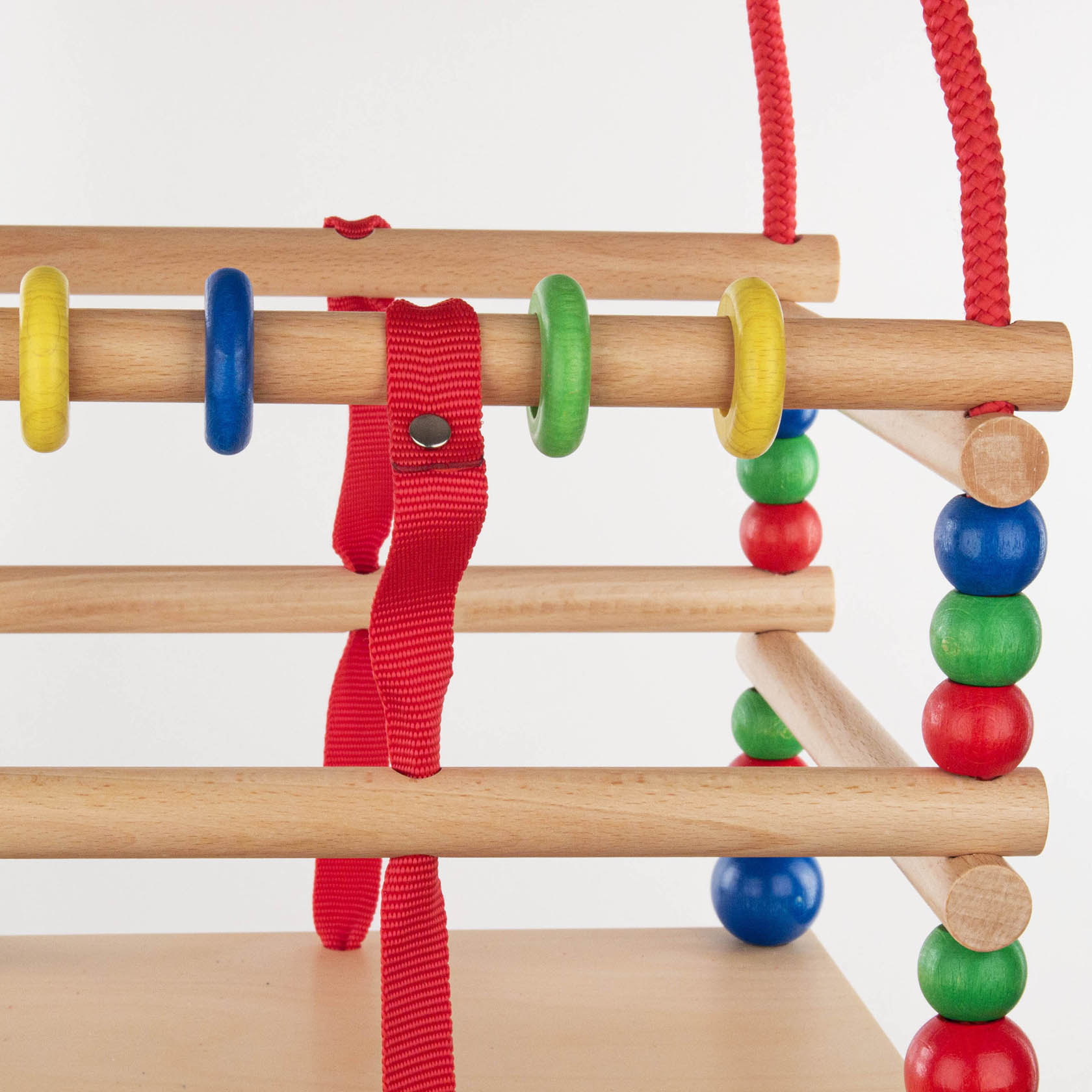 Close-up of a children's lattice swing with red ropes and colorful beads connecting wooden rods.