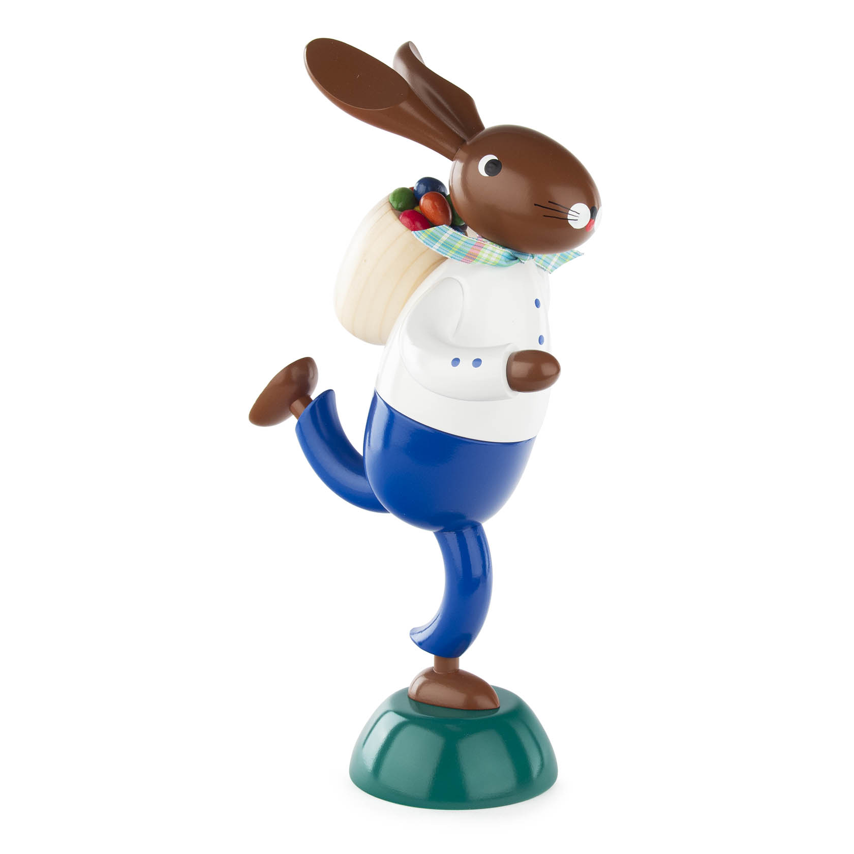 Holzfigur eines Hasen in blauer Hose und weißem Hemd, der auf einem Bein steht. Der Hase trägt eine Kiepe mit bunten Eiern auf dem Rücken. im Dregeno Online Shop günstig kaufen